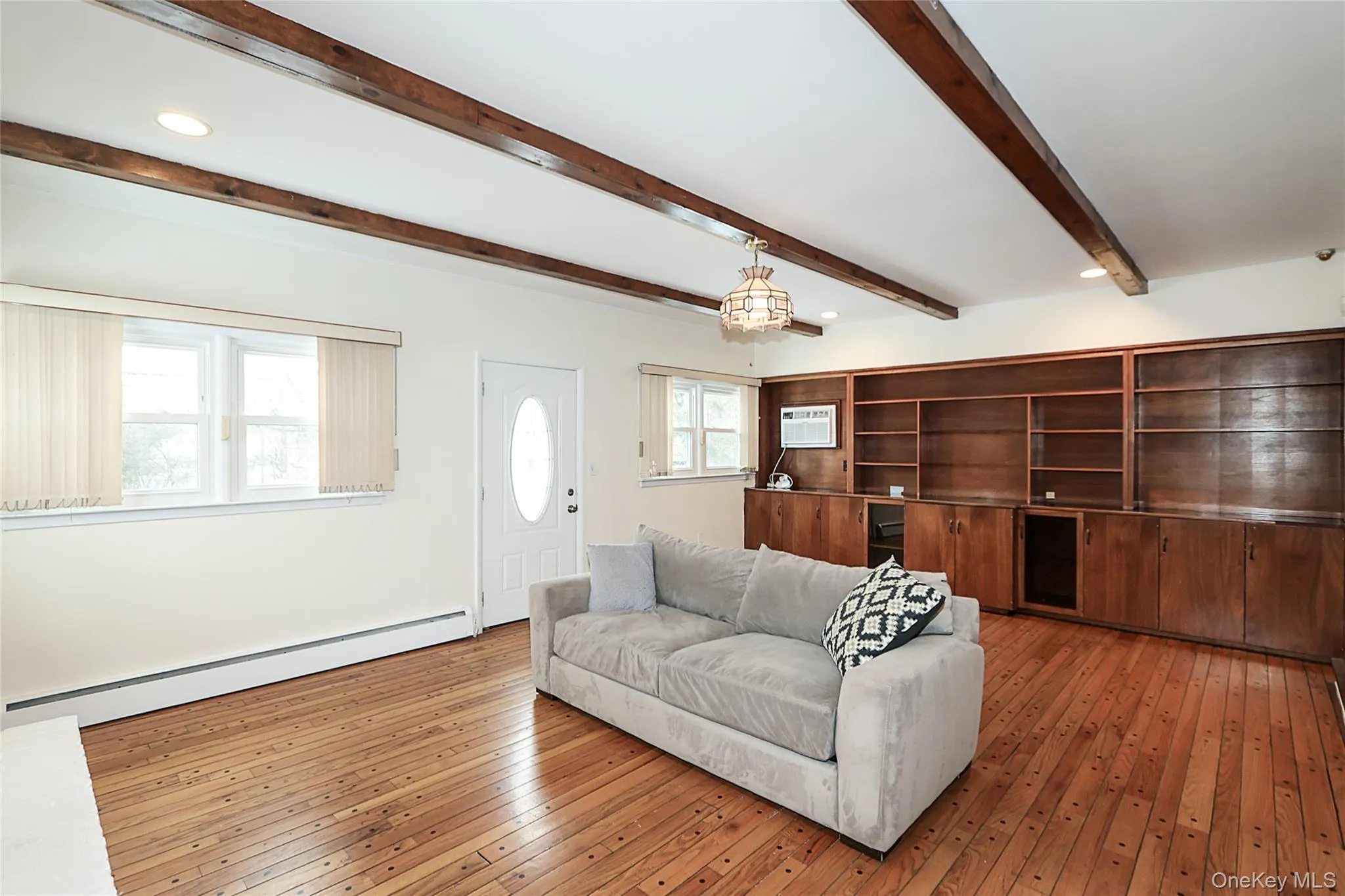 Living area with a baseboard heating unit, light wood finished floors, beam ceiling, and recessed lighting Living area with a baseboard heating unit, light wood finished floors, beam ceiling, and recessed lighting