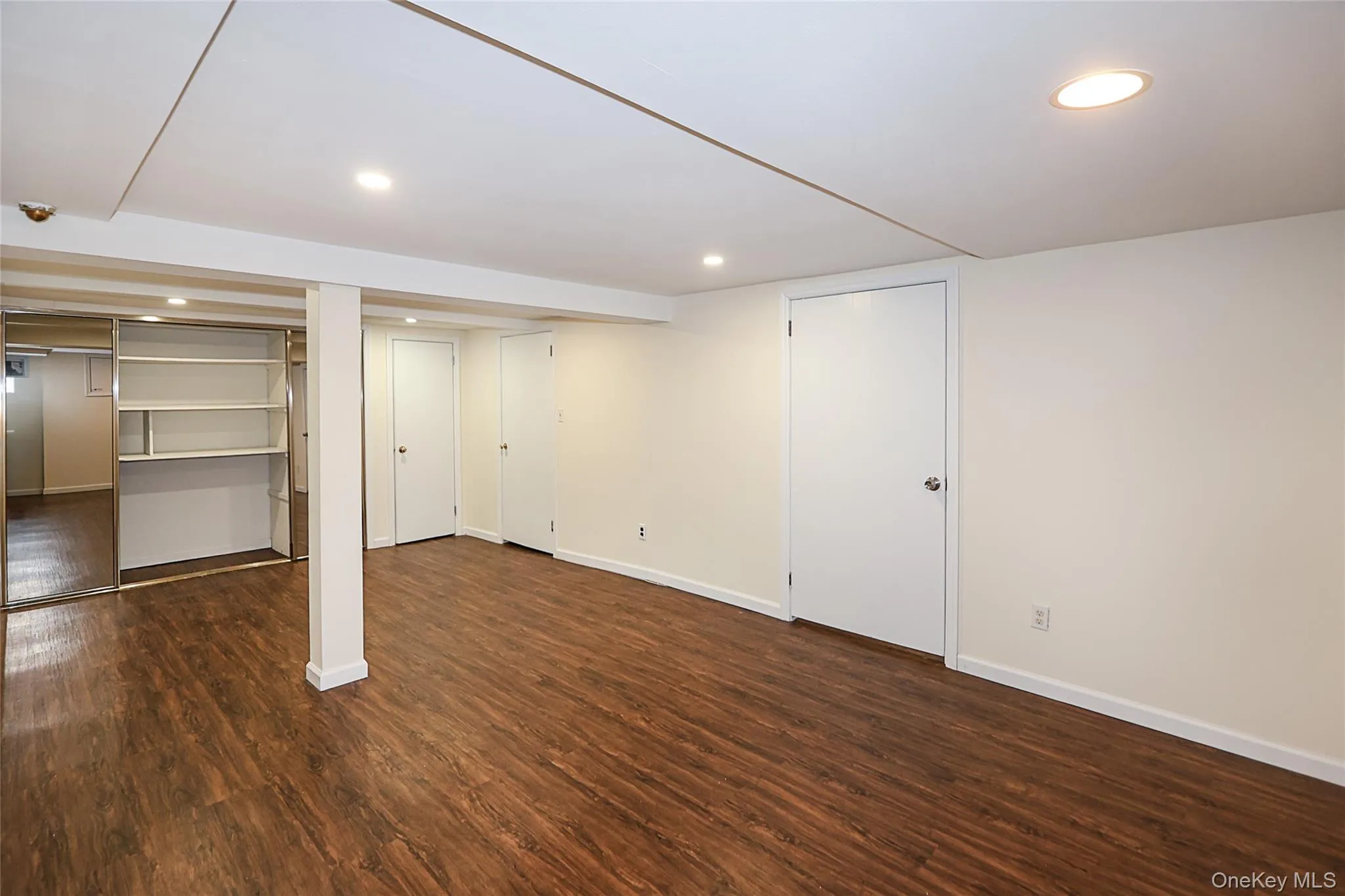 Finished basement with dark wood-style floors and recessed lighting Finished basement with dark wood-style floors and recessed lighting