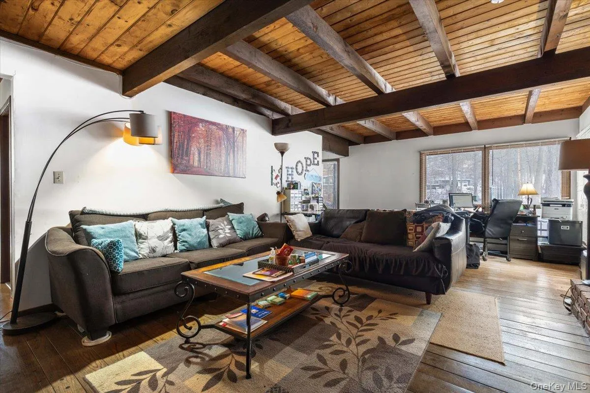 Living Room – Spacious living area with exposed wood beams and fireplace. Living Room – Spacious living area with exposed wood beams and fireplace.