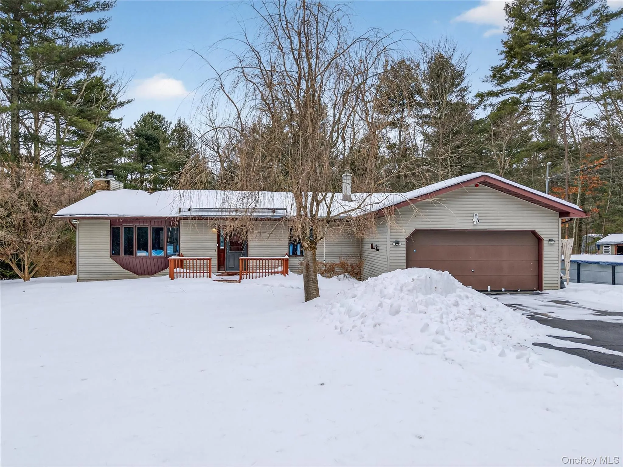 Single story home featuring a chimney, a deck, and an attached garage Single story home featuring a chimney, a deck, and an attached garage