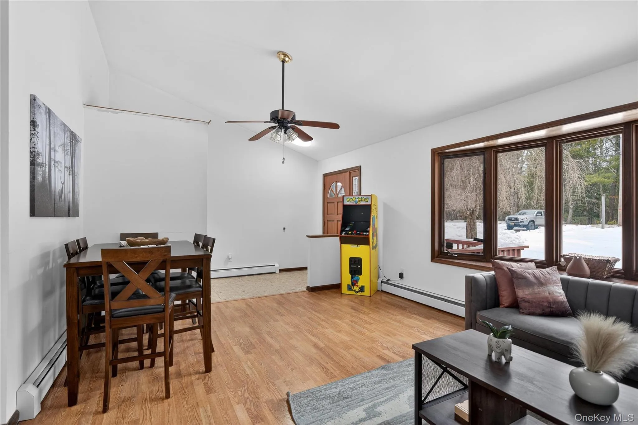 Living area featuring baseboard heating, vaulted ceiling, light wood-type flooring, and a ceiling fan Living area featuring baseboard heating, vaulted ceiling, light wood-type flooring, and a ceiling fan