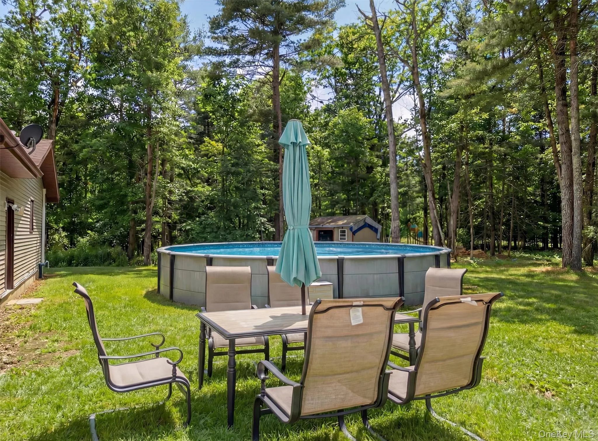 View of green lawn with a patio area, an outdoor pool, view of scattered trees, and outdoor dining area View of green lawn with a patio area, an outdoor pool, view of scattered trees, and outdoor dining area