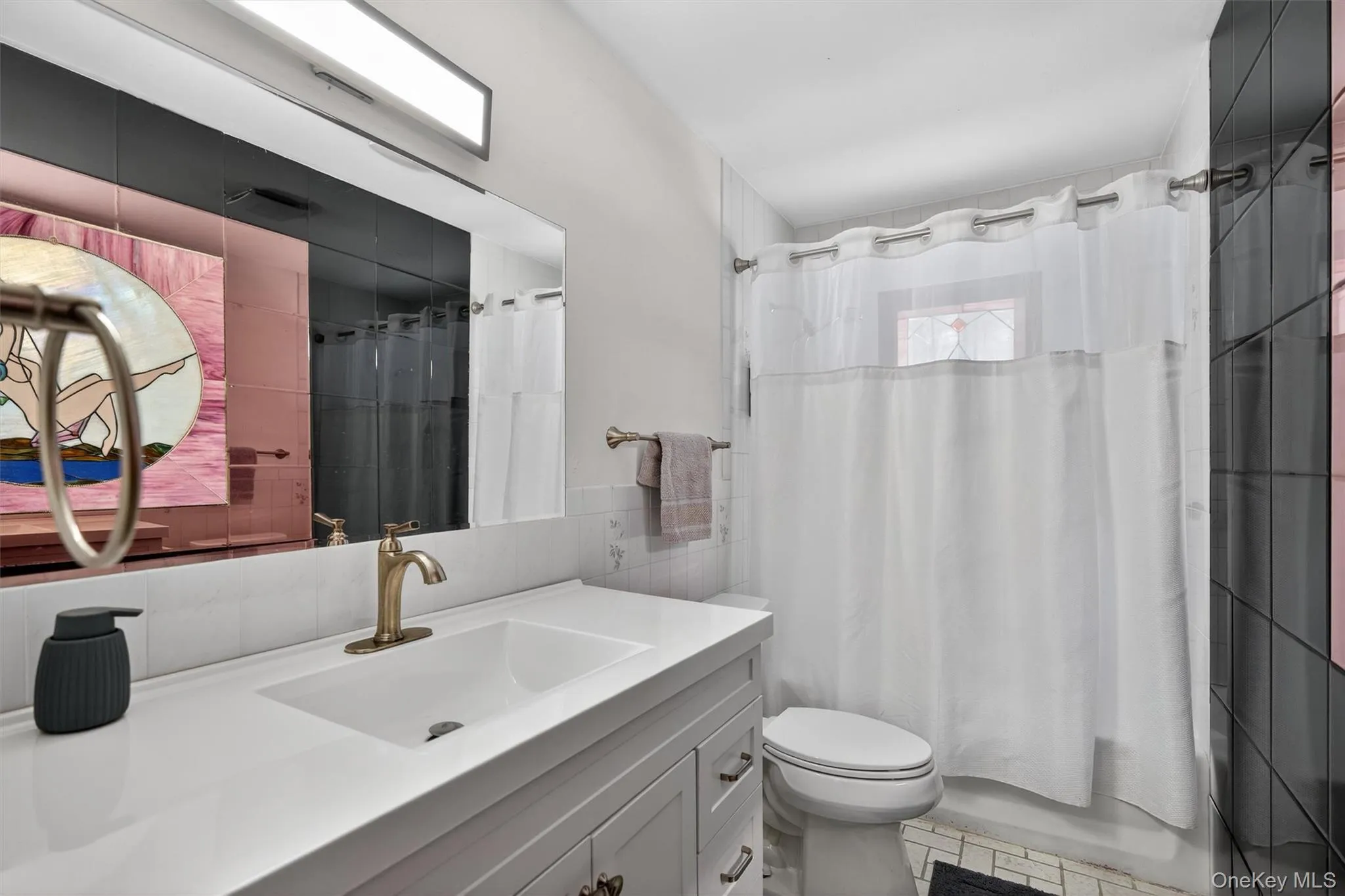 Bathroom with tile walls, vanity, and shower / bath combination with curtain Bathroom with tile walls, vanity, and shower / bath combination with curtain