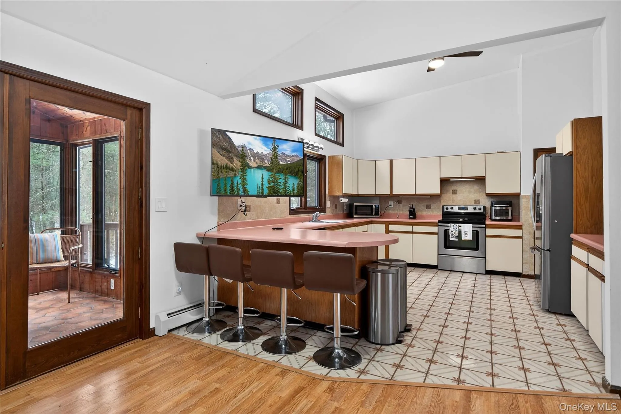 Kitchen with stainless steel appliances, a kitchen bar, a peninsula, light countertops, and lofted ceiling Kitchen with stainless steel appliances, a kitchen bar, a peninsula, light countertops, and lofted ceiling