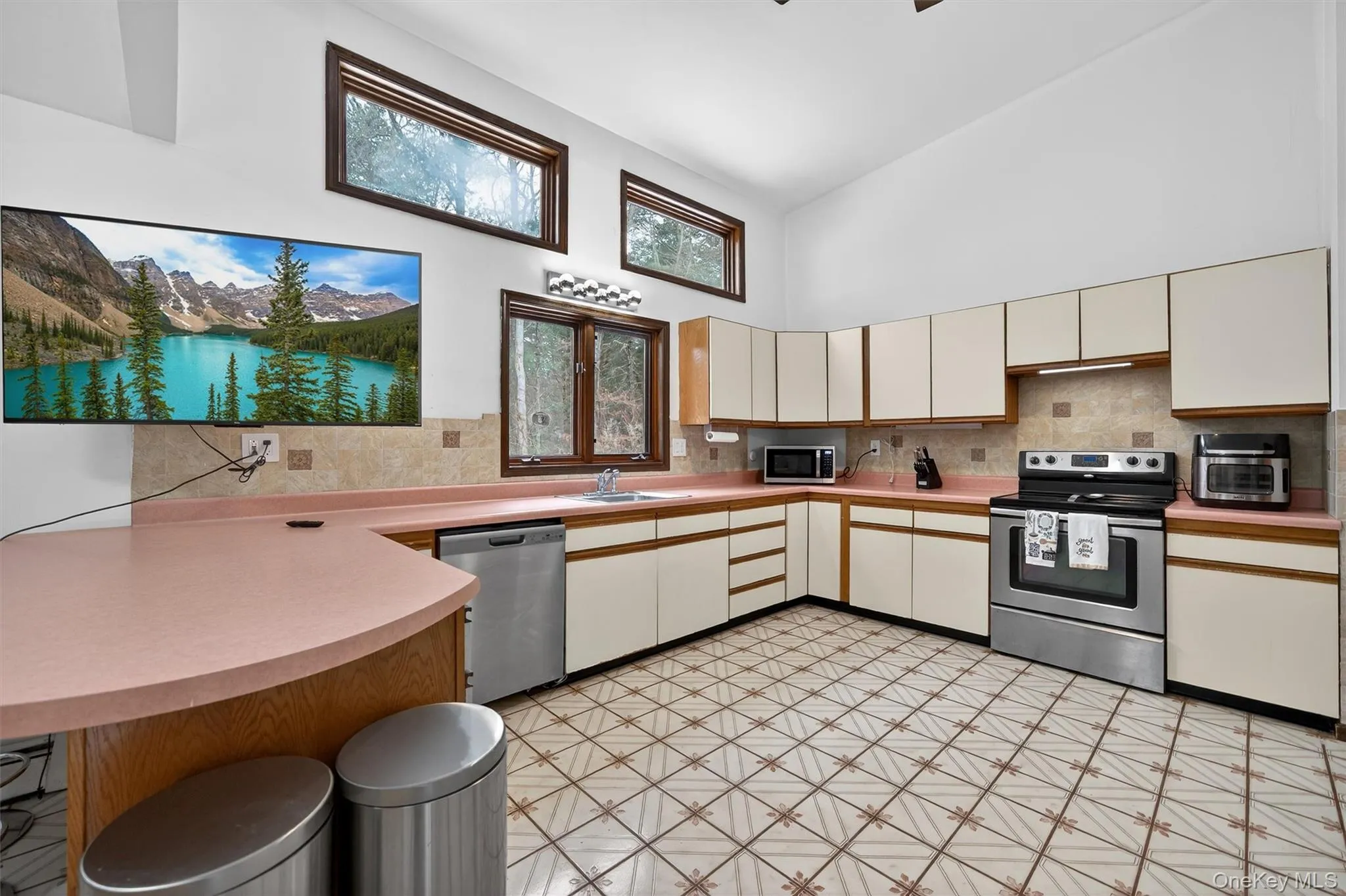 Kitchen with stainless steel appliances, two tone cabinets, light floors, light countertops, and a peninsula Kitchen with stainless steel appliances, two tone cabinets, light floors, light countertops, and a peninsula