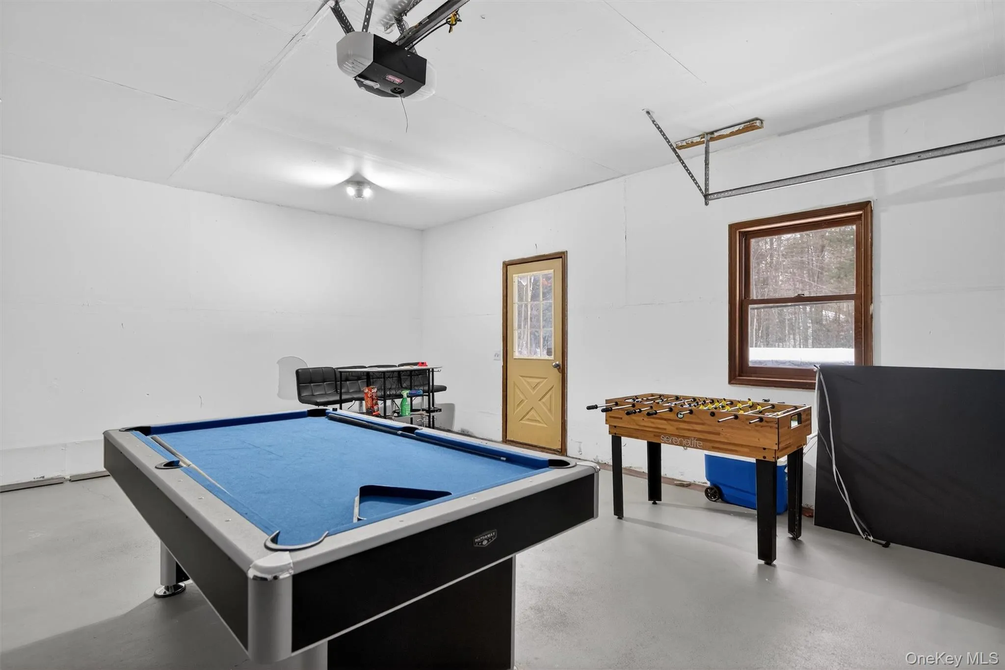 Game room featuring a garage, finished concrete flooring, and billiards table Game room featuring a garage, finished concrete flooring, and billiards table
