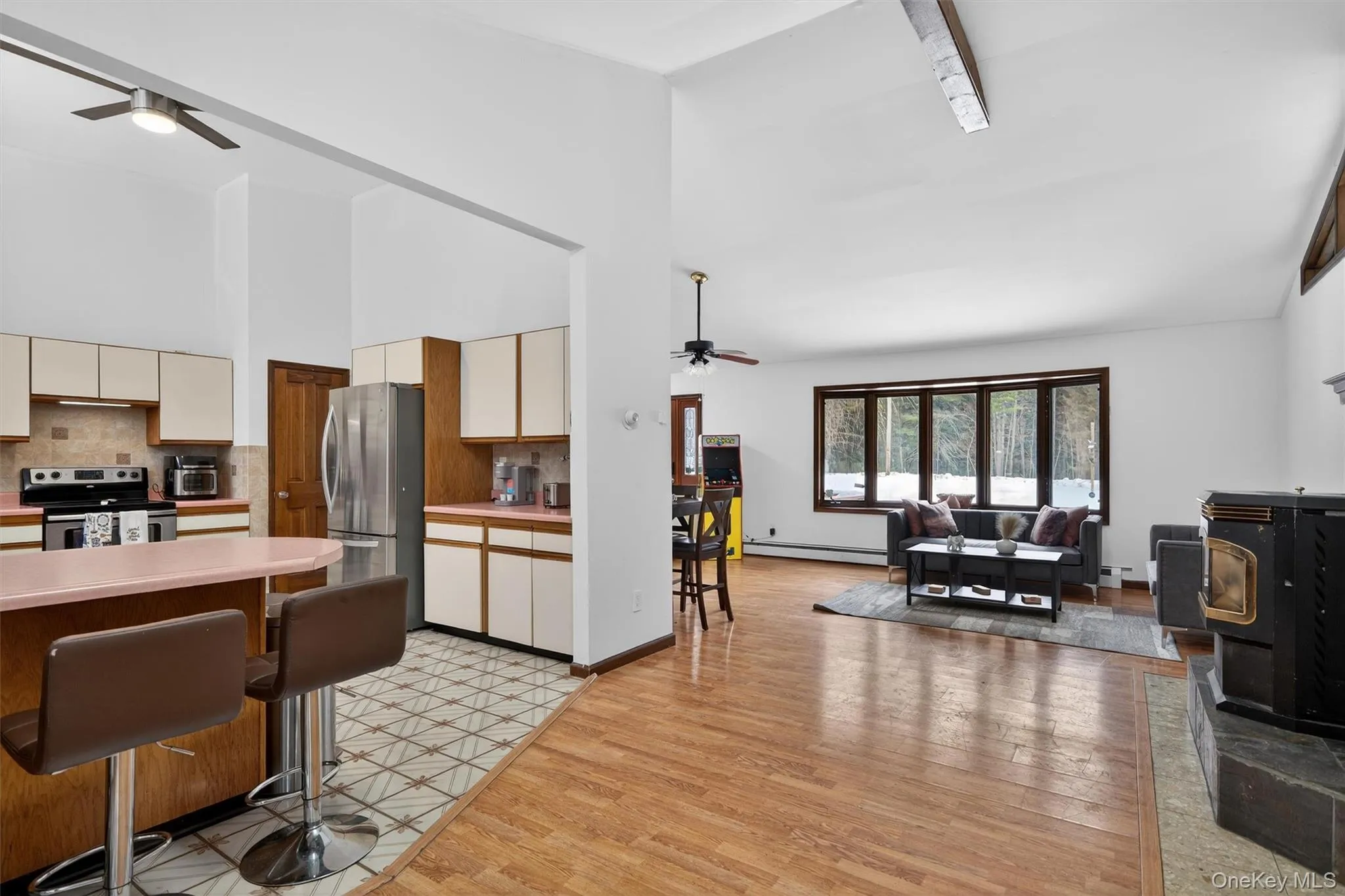 Kitchen featuring ceiling fan, light countertops, a kitchen bar, dual tone cabinets, and vaulted ceiling Kitchen featuring ceiling fan, light countertops, a kitchen bar, dual tone cabinets, and vaulted ceiling