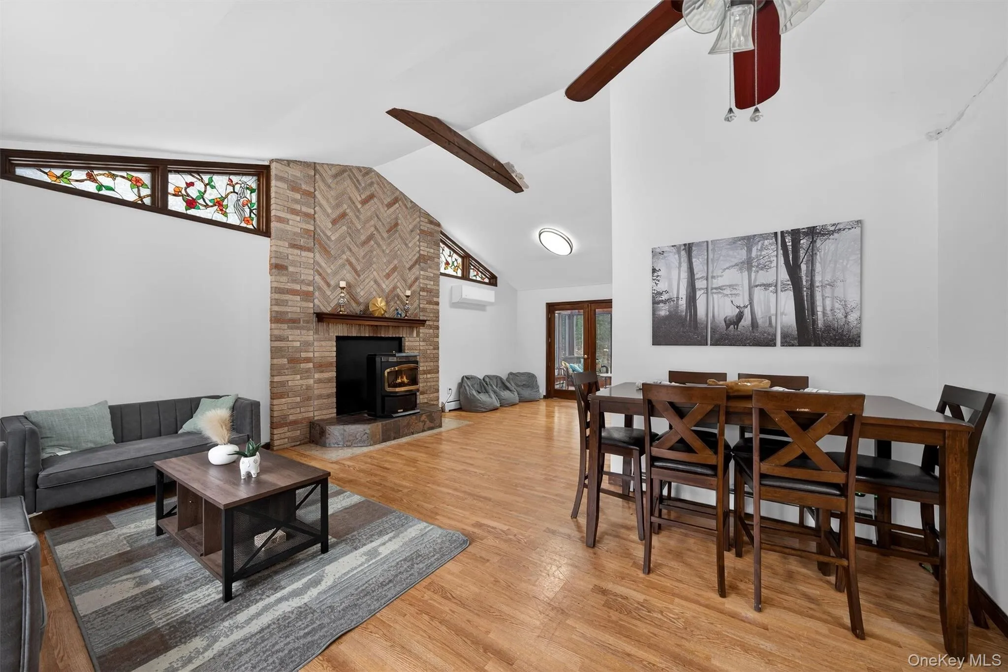 Living room with light wood-style floors, vaulted ceiling, a wood stove, and a ceiling fan Living room with light wood-style floors, vaulted ceiling, a wood stove, and a ceiling fan