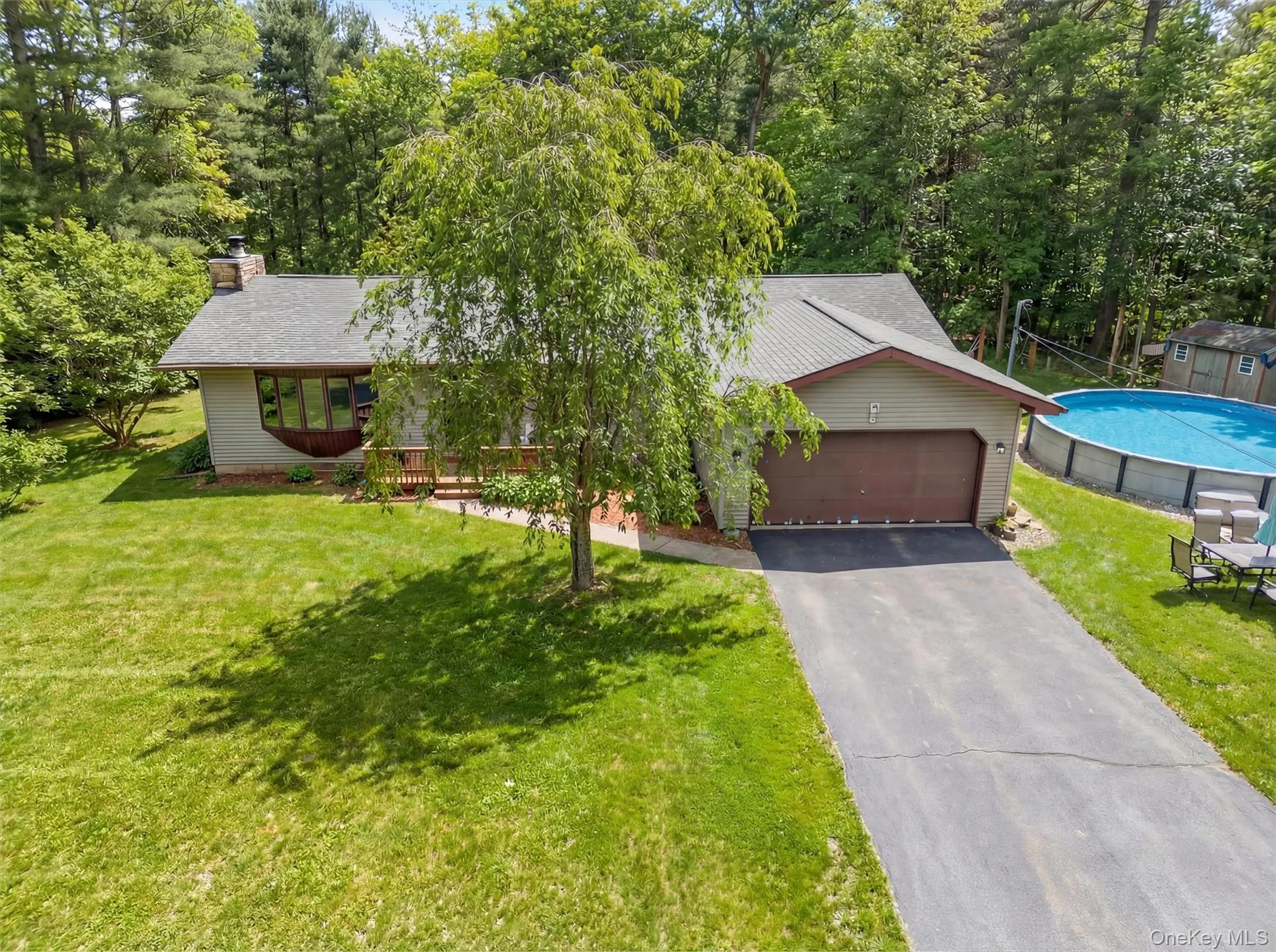 View of front of property featuring a front lawn, driveway, an attached garage, a chimney, and a shingled roof View of front of property featuring a front lawn, driveway, an attached garage, a chimney, and a shingled roof