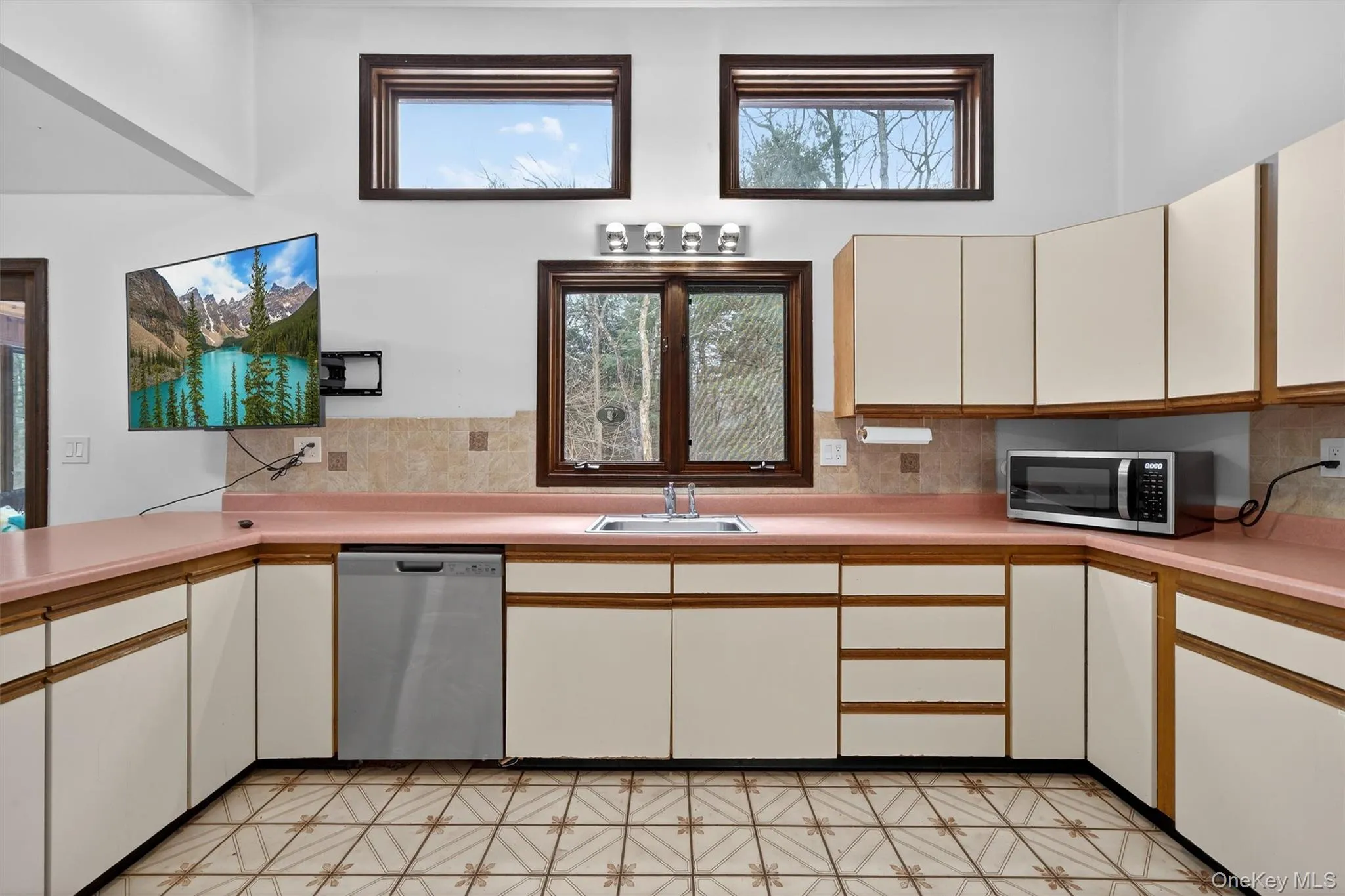 Dual tone kitchen with two tone cabinetry, light flooring, light countertops, stainless steel appliances, and plenty of natural light Dual tone kitchen with two tone cabinetry, light flooring, light countertops, stainless steel appliances, and plenty of natural light