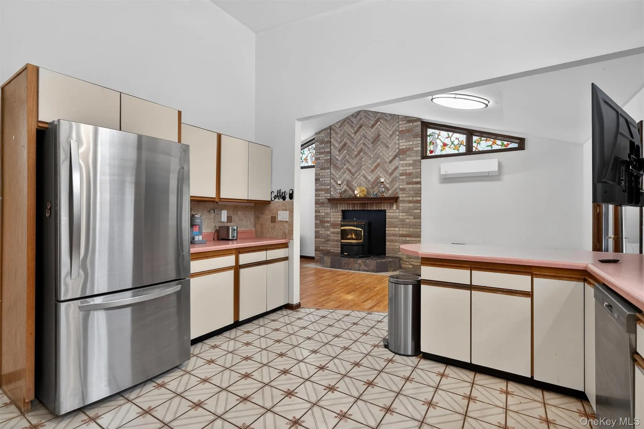 Two tone kitchen with stainless steel appliances, two tone cabinets, light countertops, open floor plan, and vaulted ceiling Two tone kitchen with stainless steel appliances, two tone cabinets, light countertops, open floor plan, and vaulted ceiling