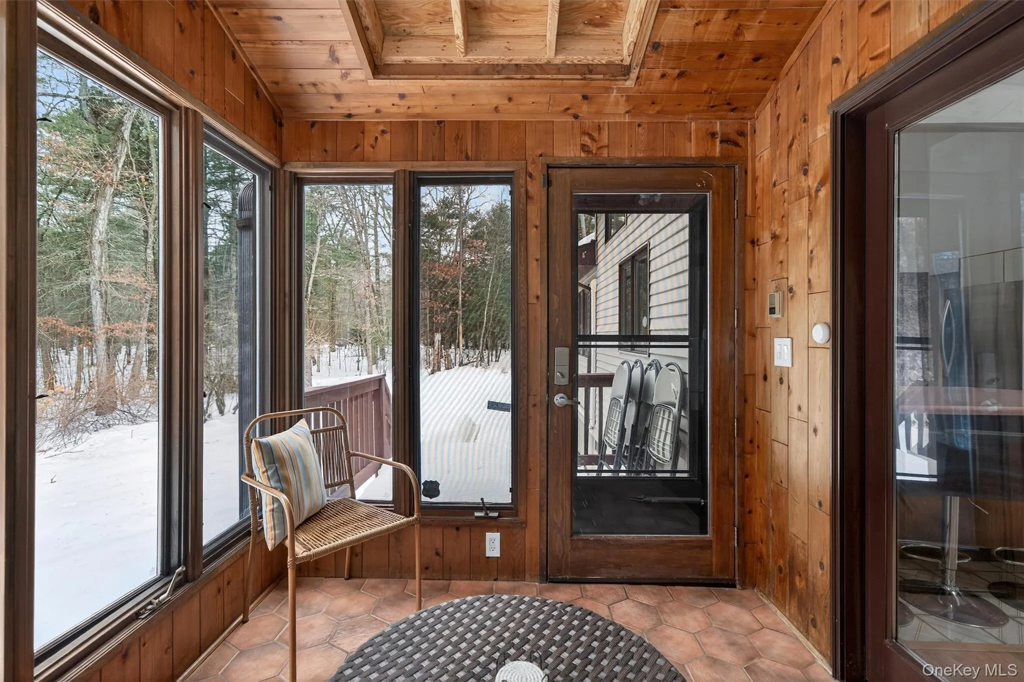 Doorway featuring wooden walls, a vaulted wooden ceiling, and tile patterned floors Doorway featuring wooden walls, a vaulted wooden ceiling, and tile patterned floors