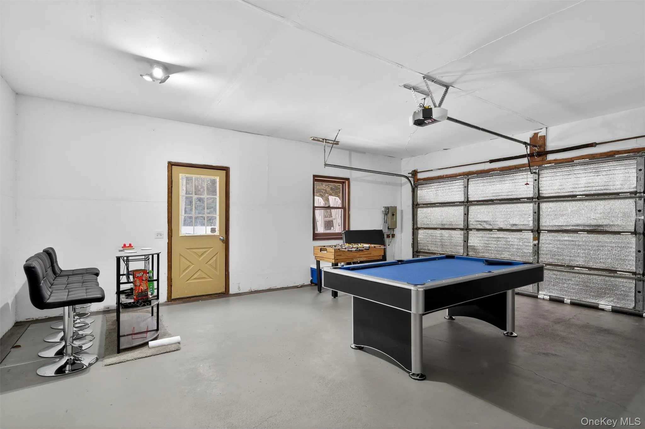 Game room featuring a garage, billiards table, and finished concrete floors Game room featuring a garage, billiards table, and finished concrete floors
