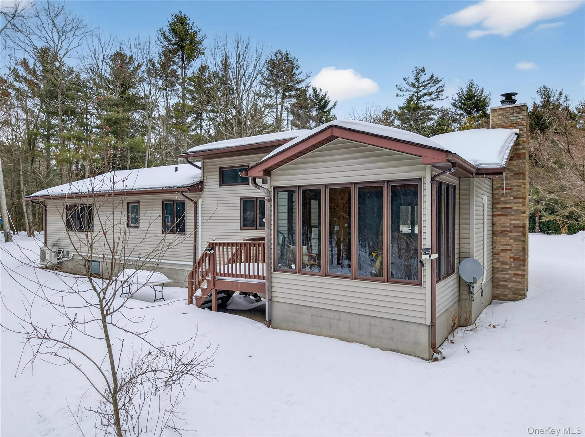 Back view of home featuring a sunroom, a chimney, and a deck Back view of home featuring a sunroom, a chimney, and a deck