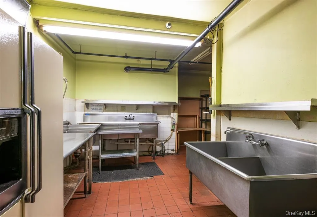 Kitchen with refrigerator with ice dispenser, stainless steel countertops, and light tile patterned floors Kitchen with refrigerator with ice dispenser, stainless steel countertops, and light tile patterned floors