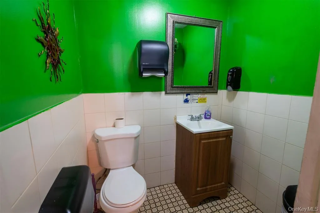 Bathroom featuring vanity, a wainscoted wall, tile walls, and tile patterned flooring Bathroom featuring vanity, a wainscoted wall, tile walls, and tile patterned flooring