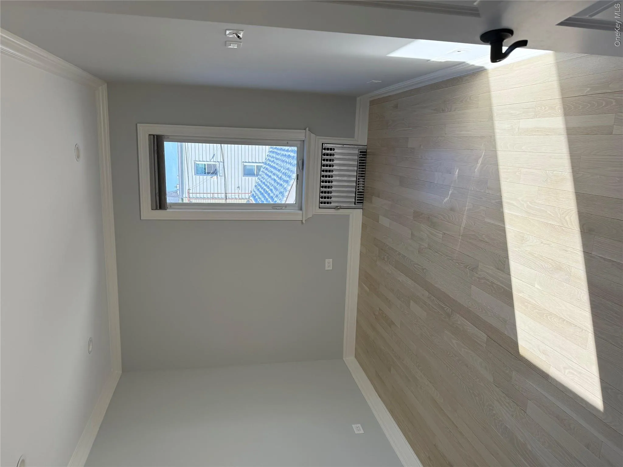 Empty room with light wood-style flooring, radiator heating unit, and crown molding Empty room with light wood-style flooring, radiator heating unit, and crown molding