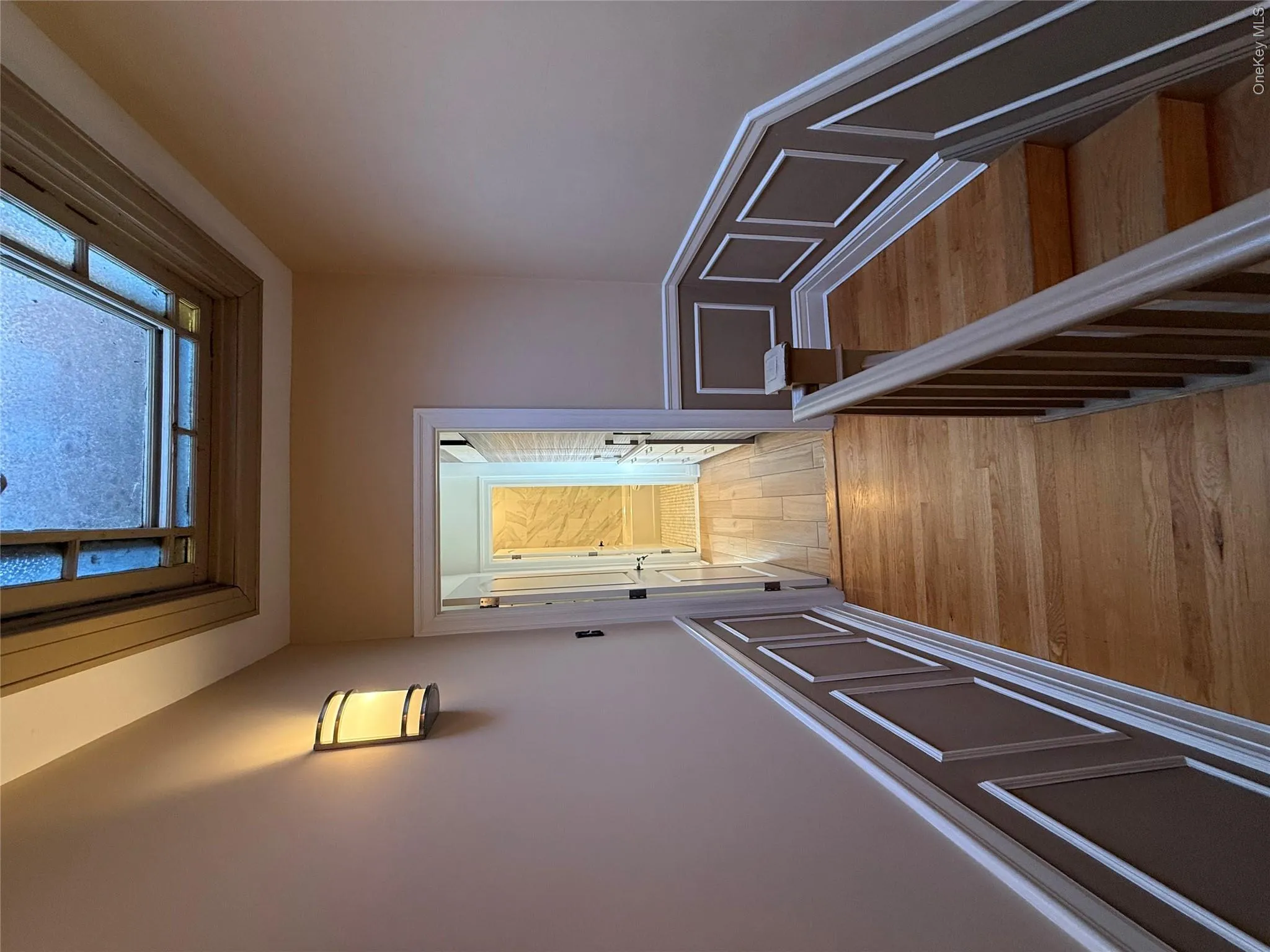 Hall with a decorative wall, wainscoting, light wood-style floors, and a skylight Hall with a decorative wall, wainscoting, light wood-style floors, and a skylight
