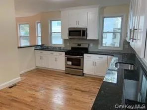 Kitchen with Appliances with Stainless steel finish dark stone counters, and white cabinetry Kitchen with Appliances with Stainless steel finish dark stone counters, and white cabinetry