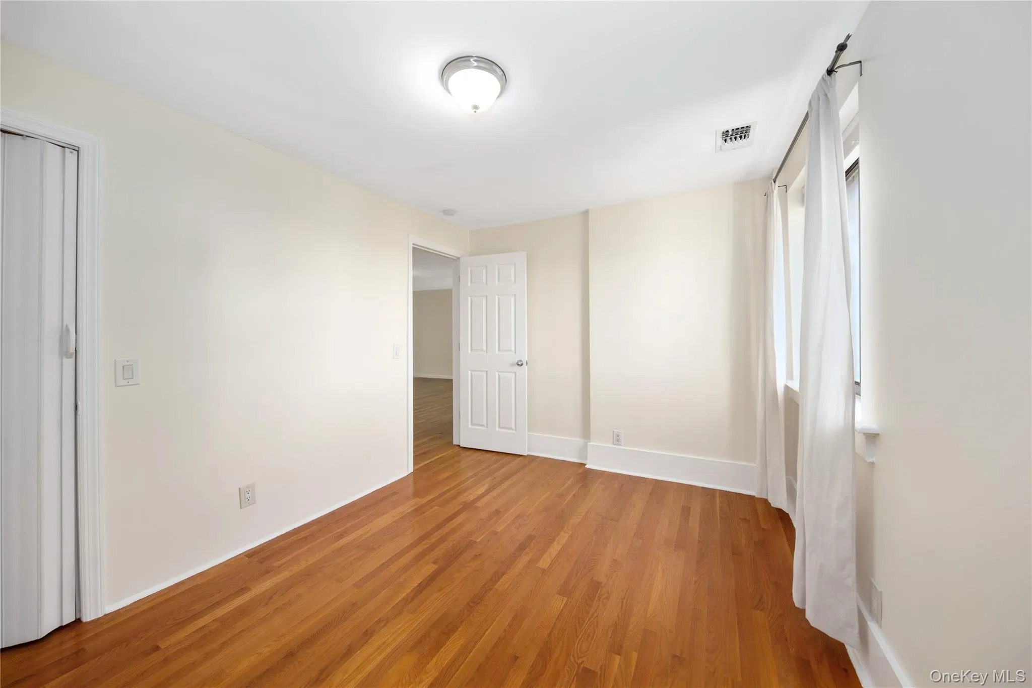 Unfurnished room with light wood-style floors and baseboards Unfurnished room with light wood-style floors and baseboards
