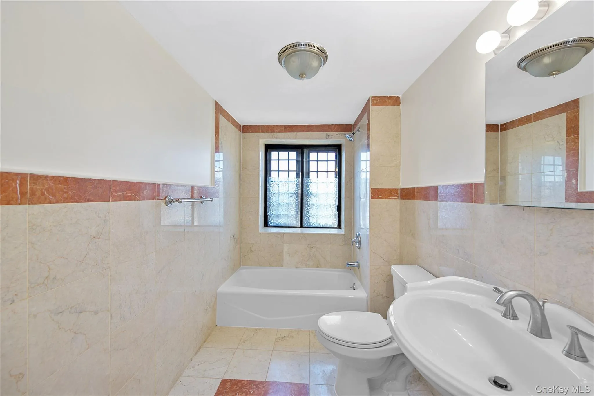 Full bath with tile walls, shower / bath combination, wainscoting, and tile patterned floors Full bath with tile walls, shower / bath combination, wainscoting, and tile patterned floors
