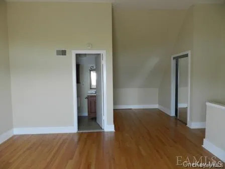 Unfurnished room with wood-type flooring and vaulted ceiling Unfurnished room with wood-type flooring and vaulted ceiling
