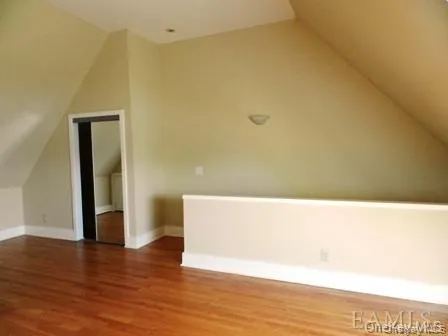 Additional living space with vaulted ceiling and dark hardwood / wood-style floors Additional living space with vaulted ceiling and dark hardwood / wood-style floors