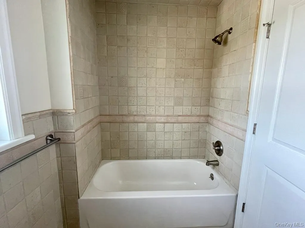 Bathtub with shower and stone tile in bathroom Bathtub with shower and stone tile in bathroom