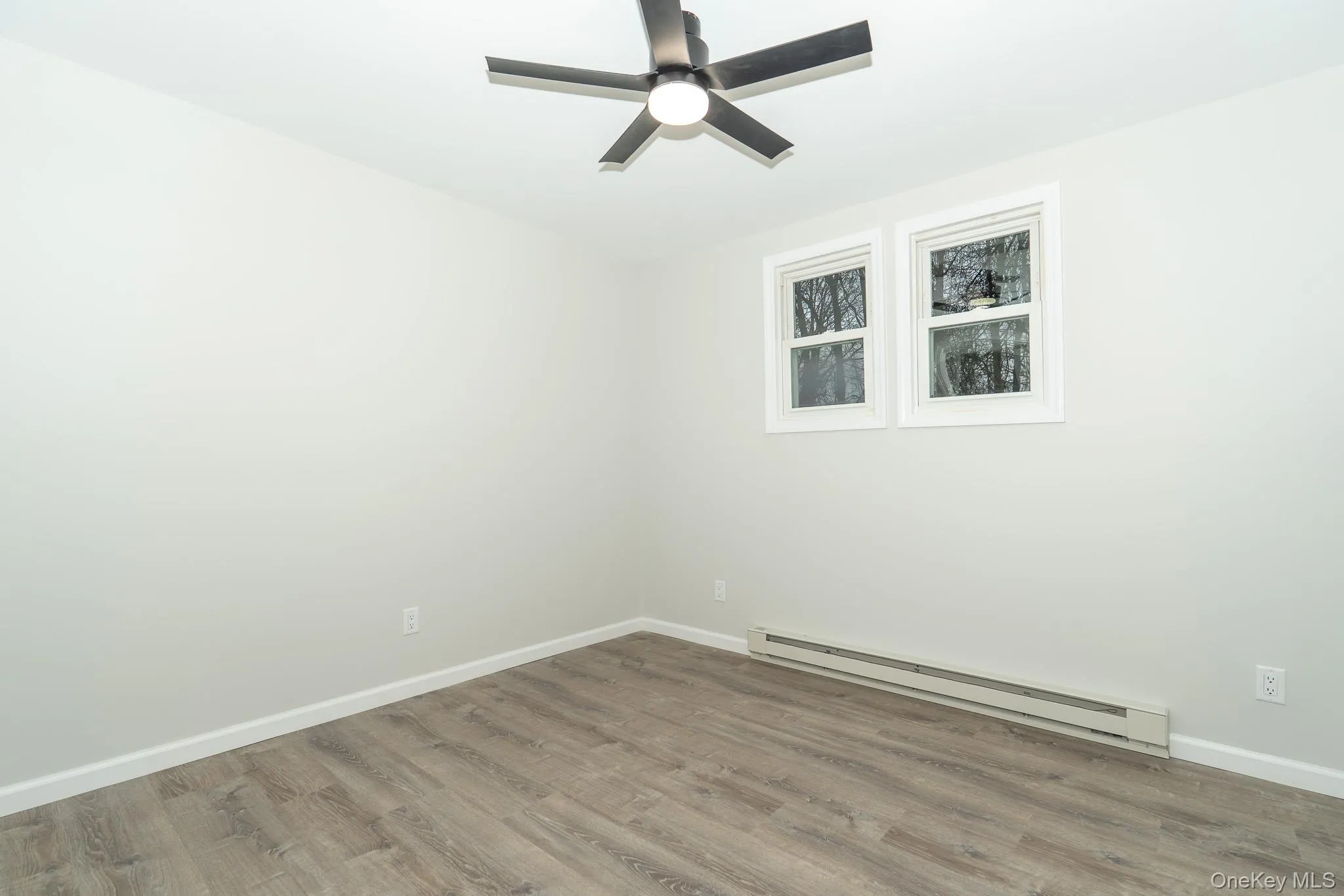 Spare room with baseboards, baseboard heating, wood finished floors, and ceiling fan Spare room with baseboards, baseboard heating, wood finished floors, and ceiling fan