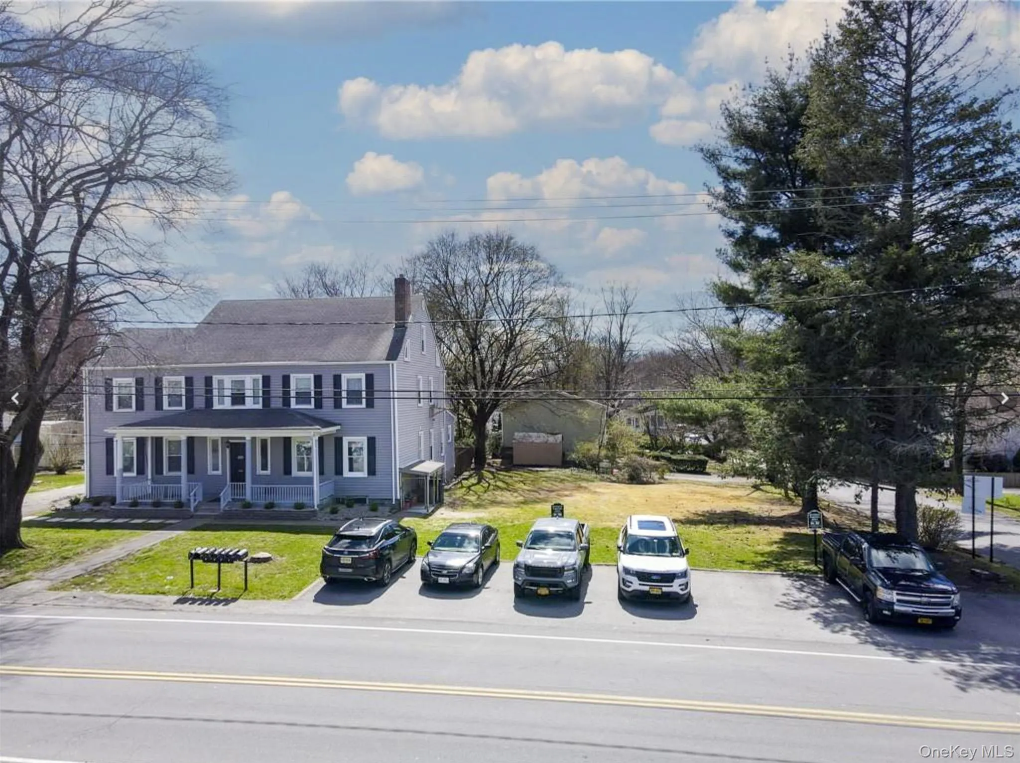 View of front of house featuring a chimney, uncovered parking, and a front yard View of front of house featuring a chimney, uncovered parking, and a front yard