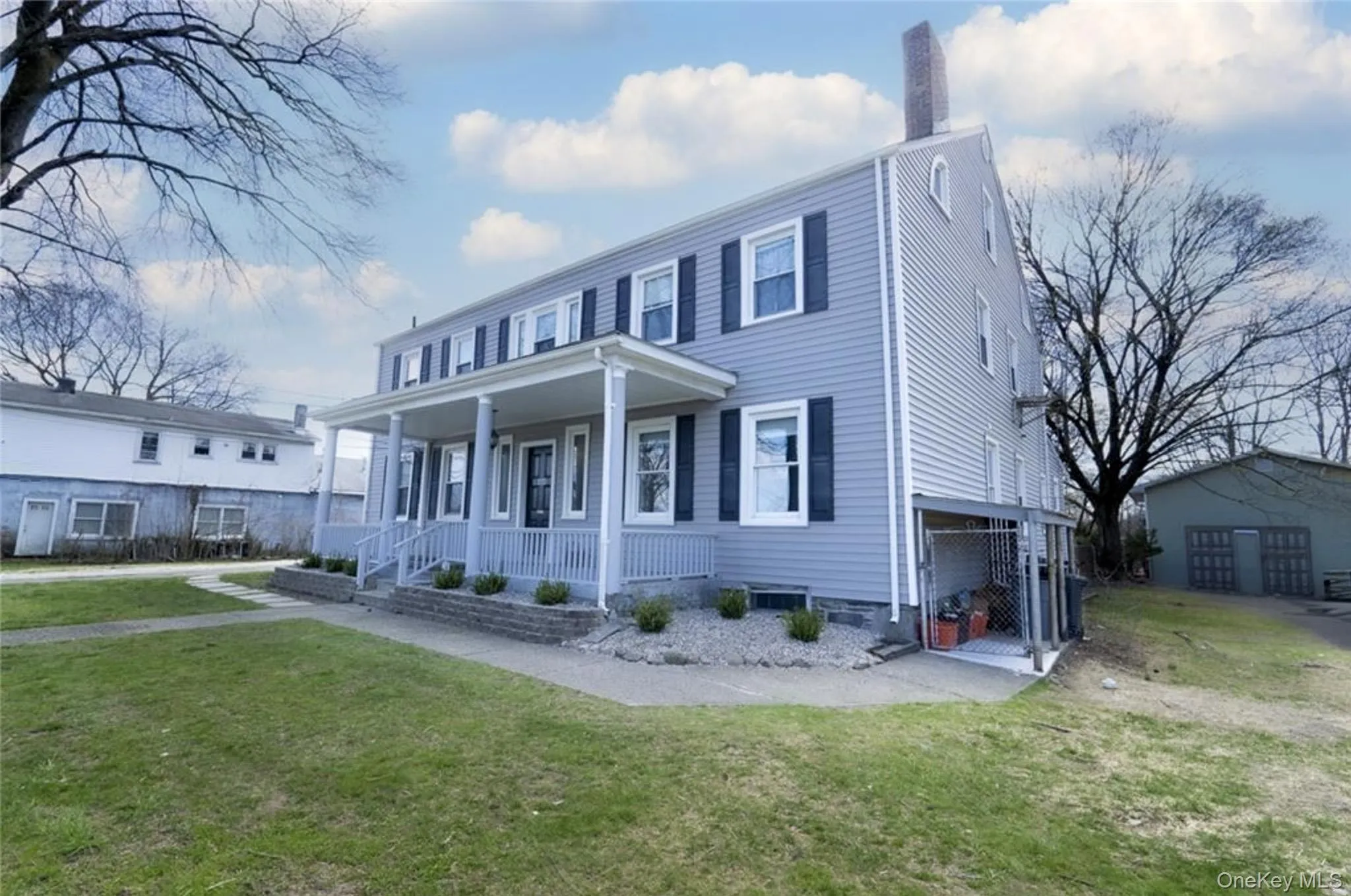 View of front of house with a front yard, a porch, and a chimney View of front of house with a front yard, a porch, and a chimney