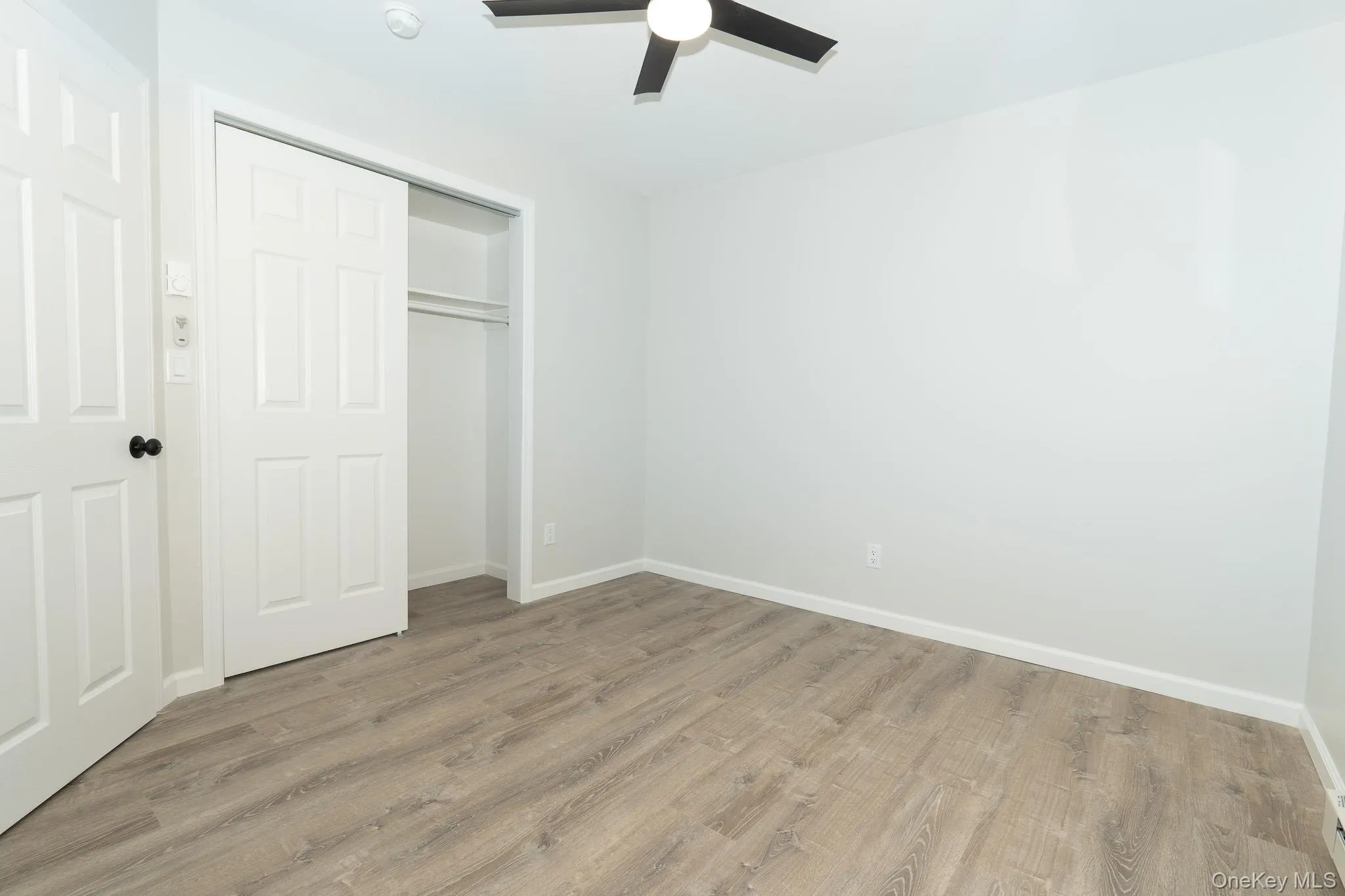 Unfurnished bedroom with a closet, a ceiling fan, baseboards, and light wood-type flooring Unfurnished bedroom with a closet, a ceiling fan, baseboards, and light wood-type flooring