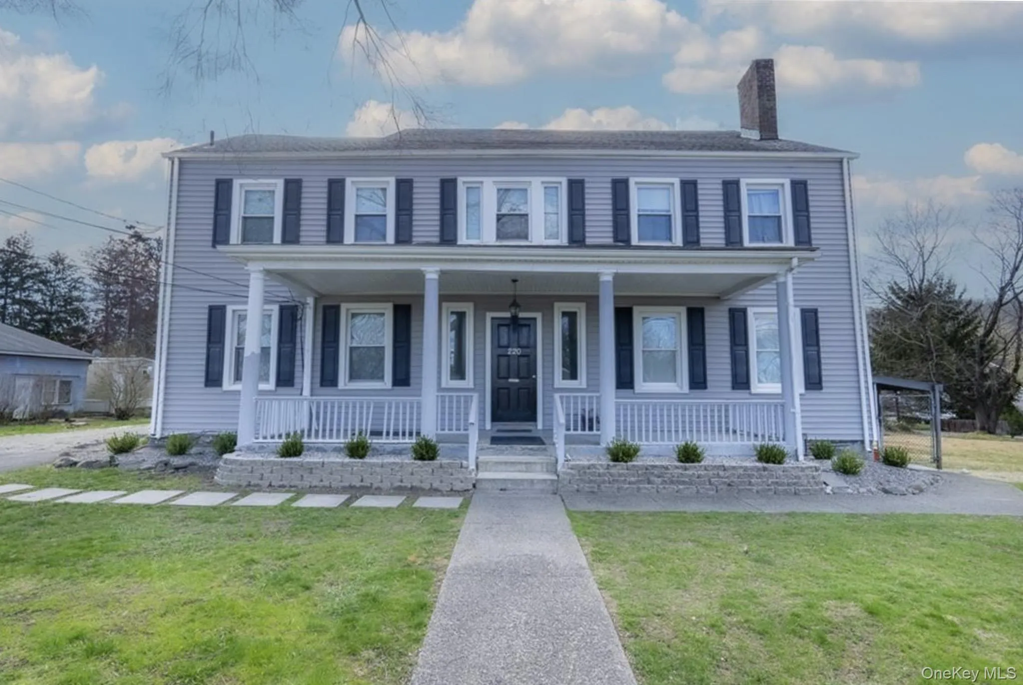 Colonial-style house with covered porch, a front lawn, and a chimney Colonial-style house with covered porch, a front lawn, and a chimney