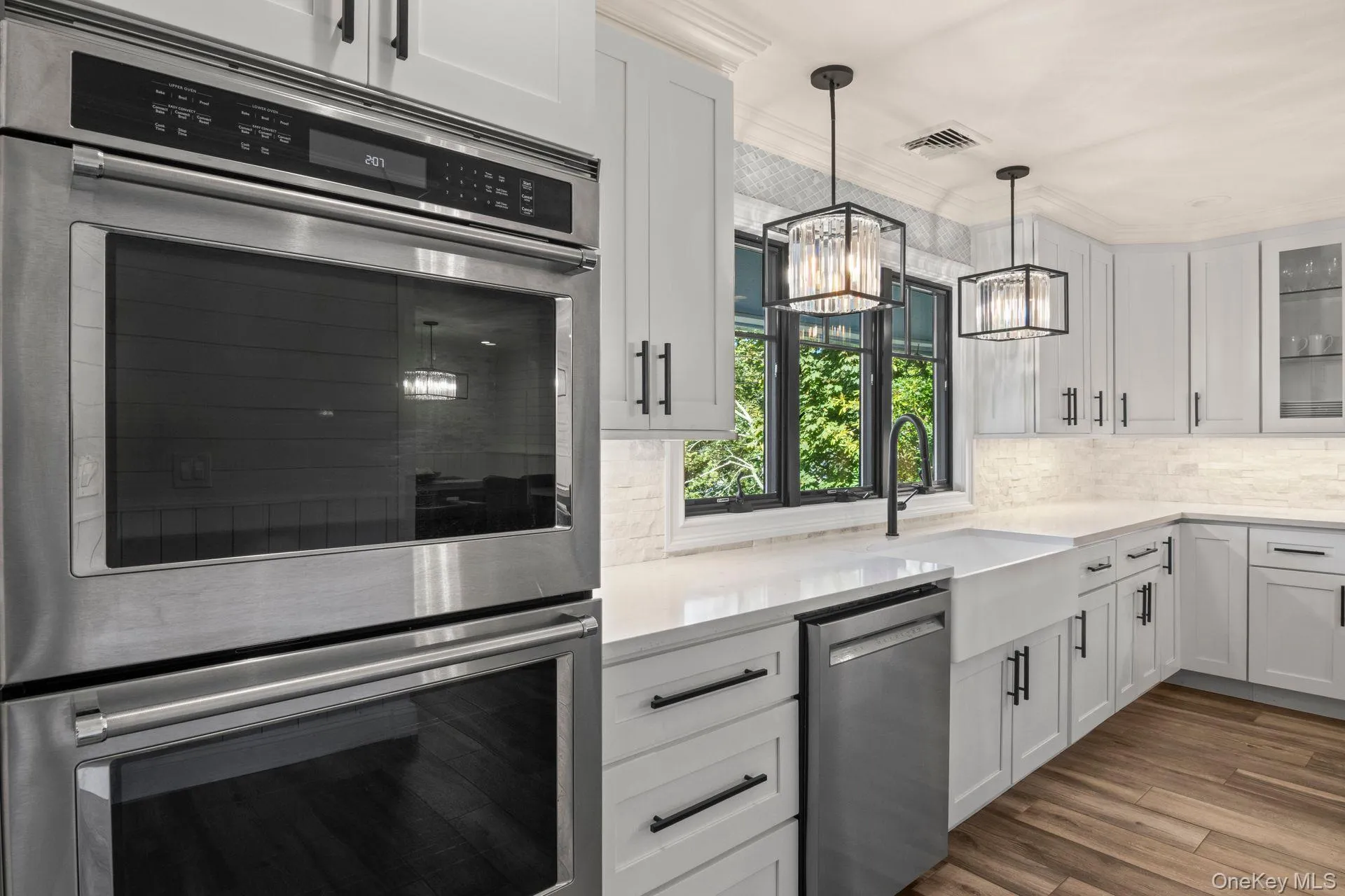 Double wall ovens, white cabinetry, decorative backsplash, and glass insert cabinets Double wall ovens, white cabinetry, decorative backsplash, and glass insert cabinets