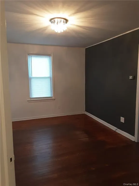 Empty room featuring dark wood-type flooring and baseboards Empty room featuring dark wood-type flooring and baseboards