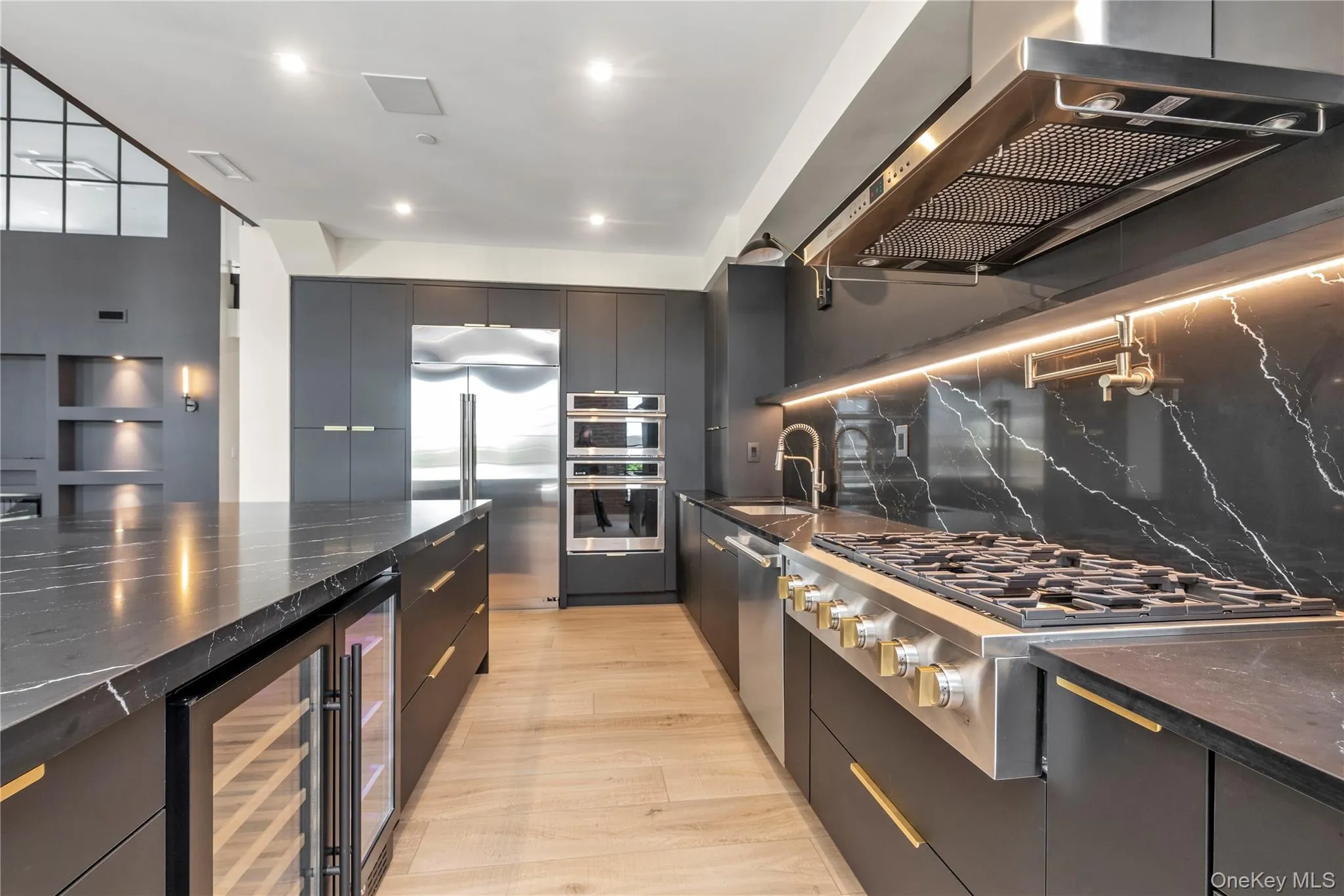 Kitchen featuring wall chimney range hood, modern cabinets, top of the line stainless steel appliances, beverage cooler and wine fridge, and tons of storage. Kitchen featuring wall chimney range hood, modern cabinets, top of the line stainless steel appliances, beverage cooler and wine fridge, and tons of storage.