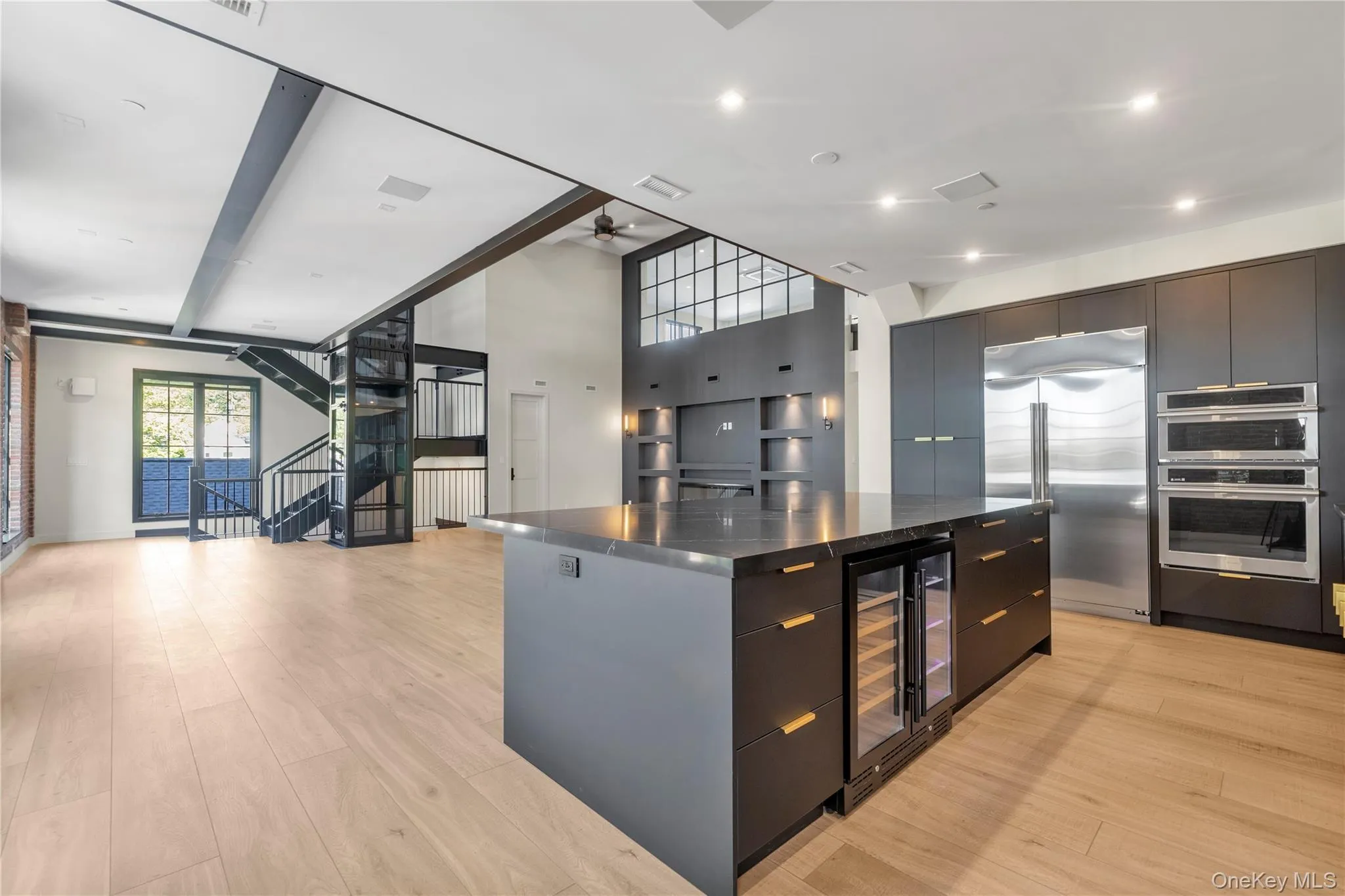 Kitchen featuring wine cooler, modern cabinets, appliances with stainless steel finishes, a center island, and light wood-style flooring Kitchen featuring wine cooler, modern cabinets, appliances with stainless steel finishes, a center island, and light wood-style flooring