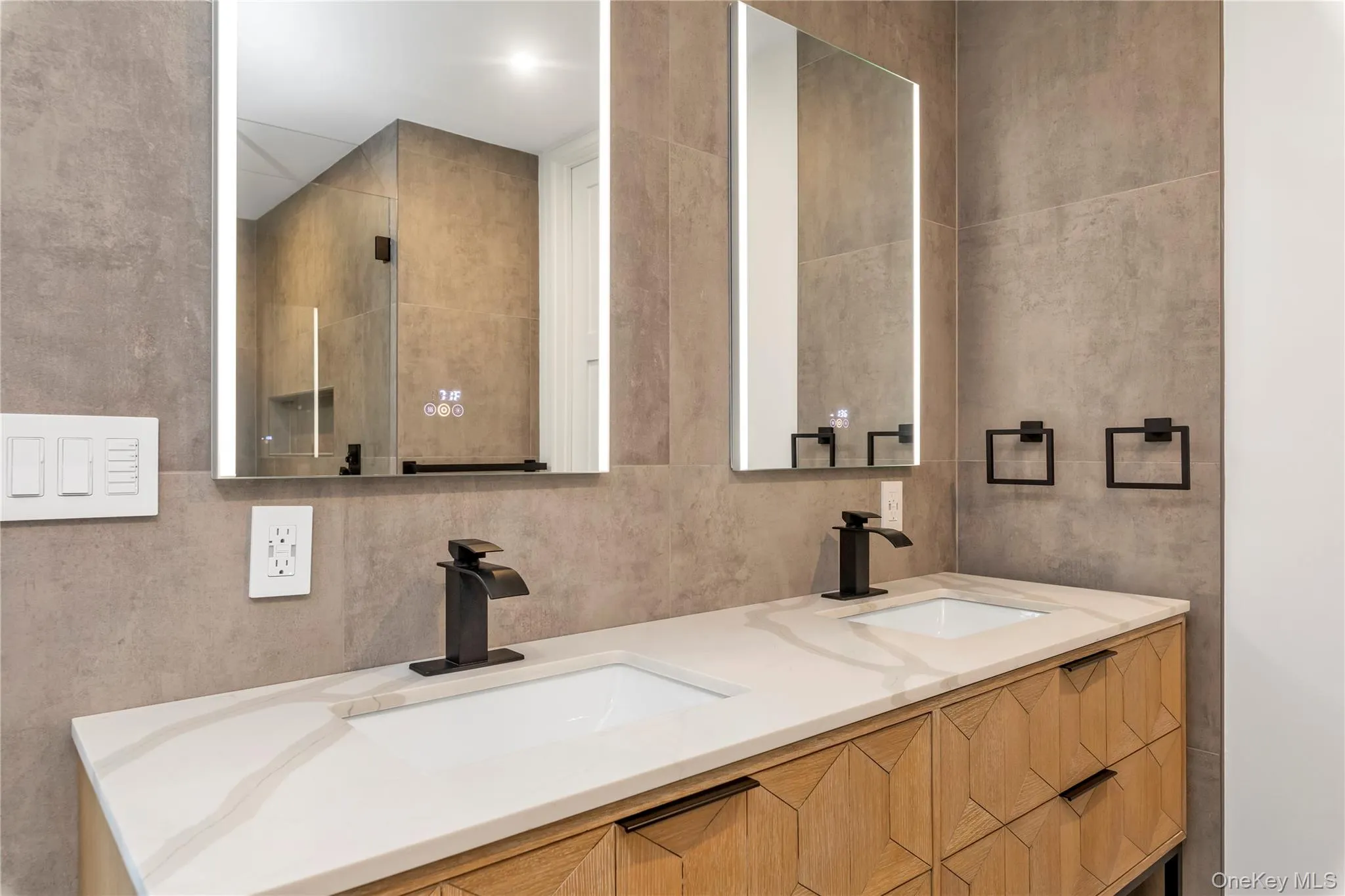 Bathroom featuring double vanity, tile walls, and a shower Bathroom featuring double vanity, tile walls, and a shower