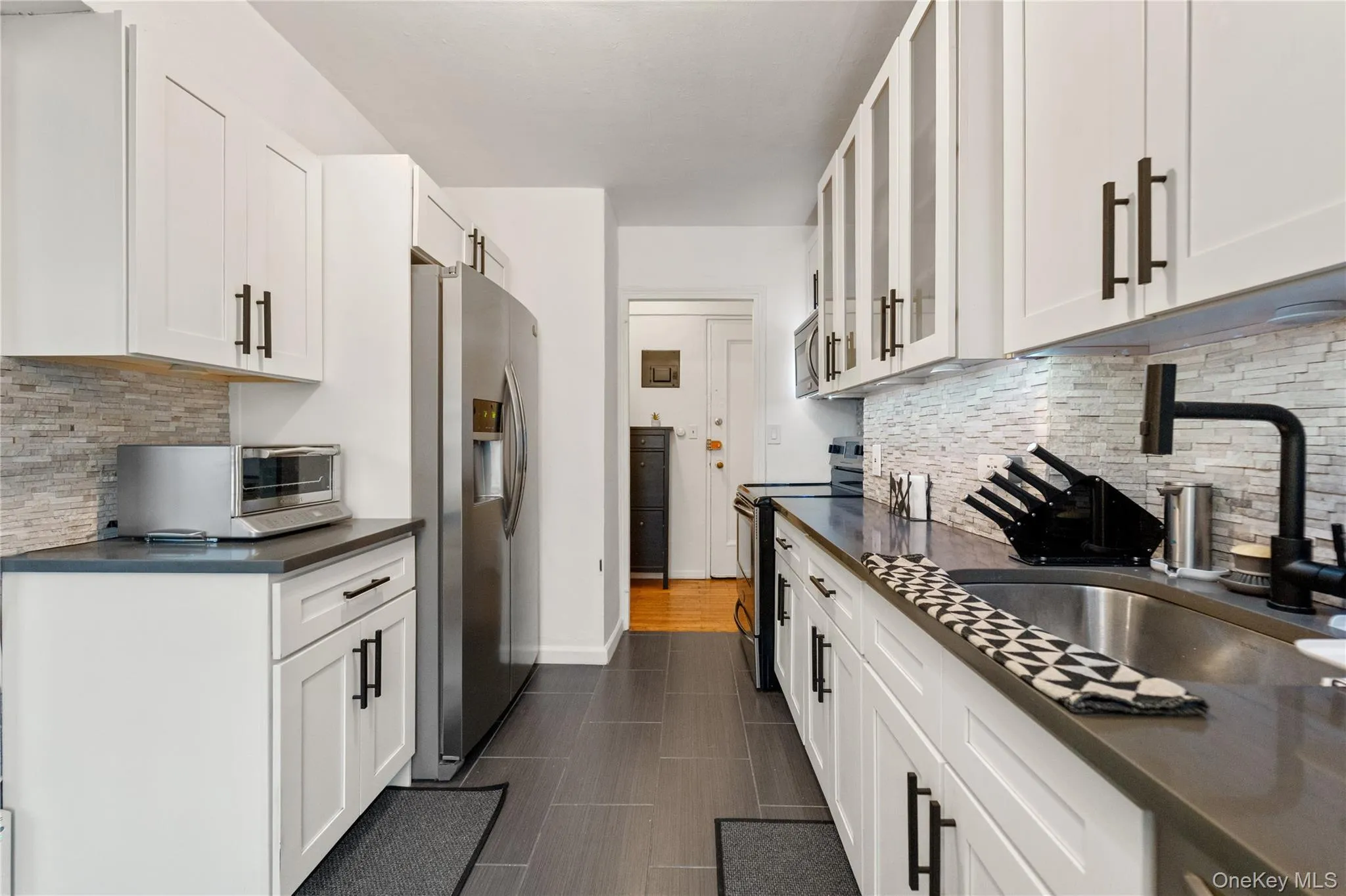 Kitchen with stainless steel appliances, tasteful backsplash, glass fronted cabinets, and white cabinets Kitchen with stainless steel appliances, tasteful backsplash, glass fronted cabinets, and white cabinets