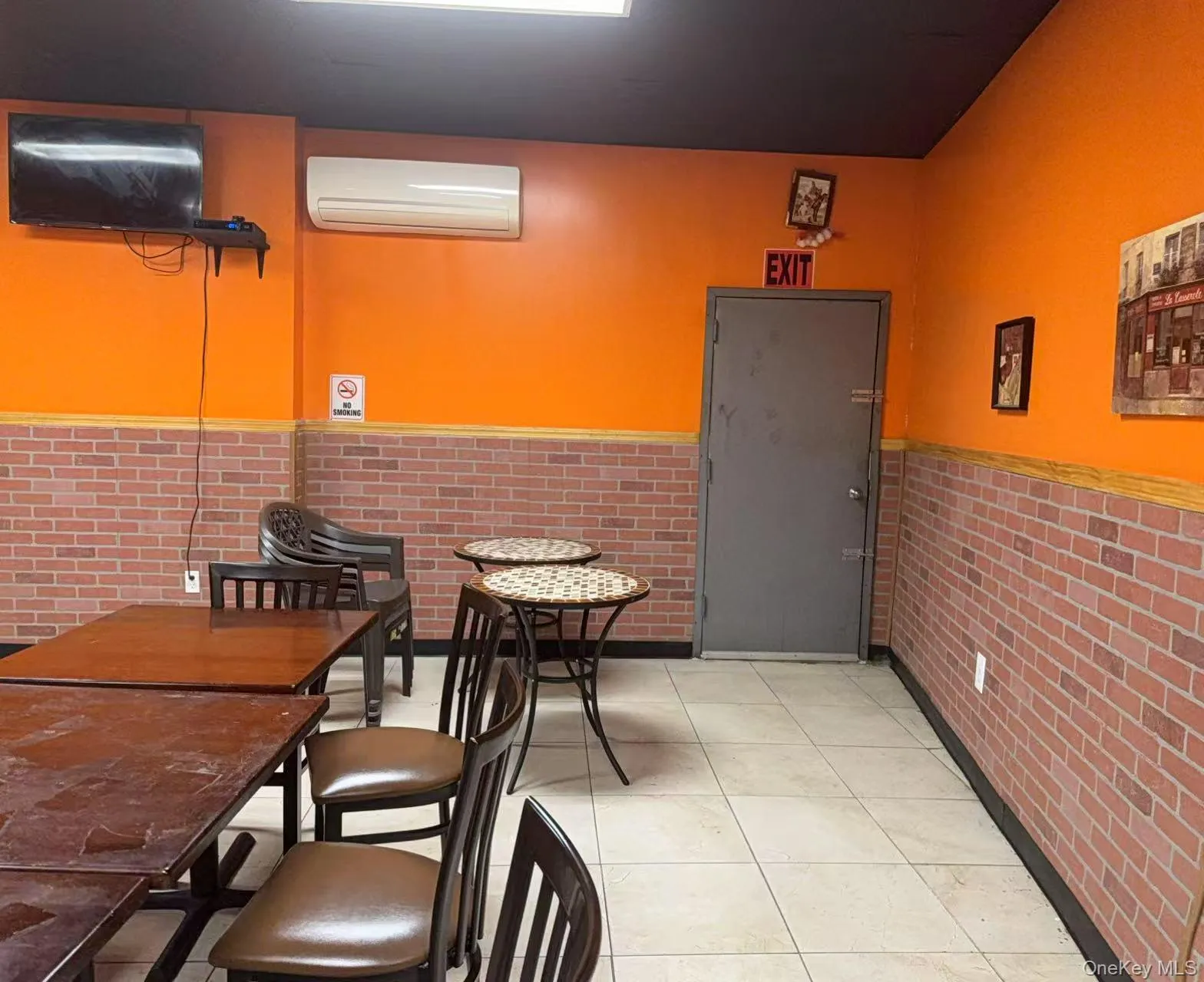 Dining room with a wall mounted AC, light tile patterned floors, and brick wall Dining room with a wall mounted AC, light tile patterned floors, and brick wall