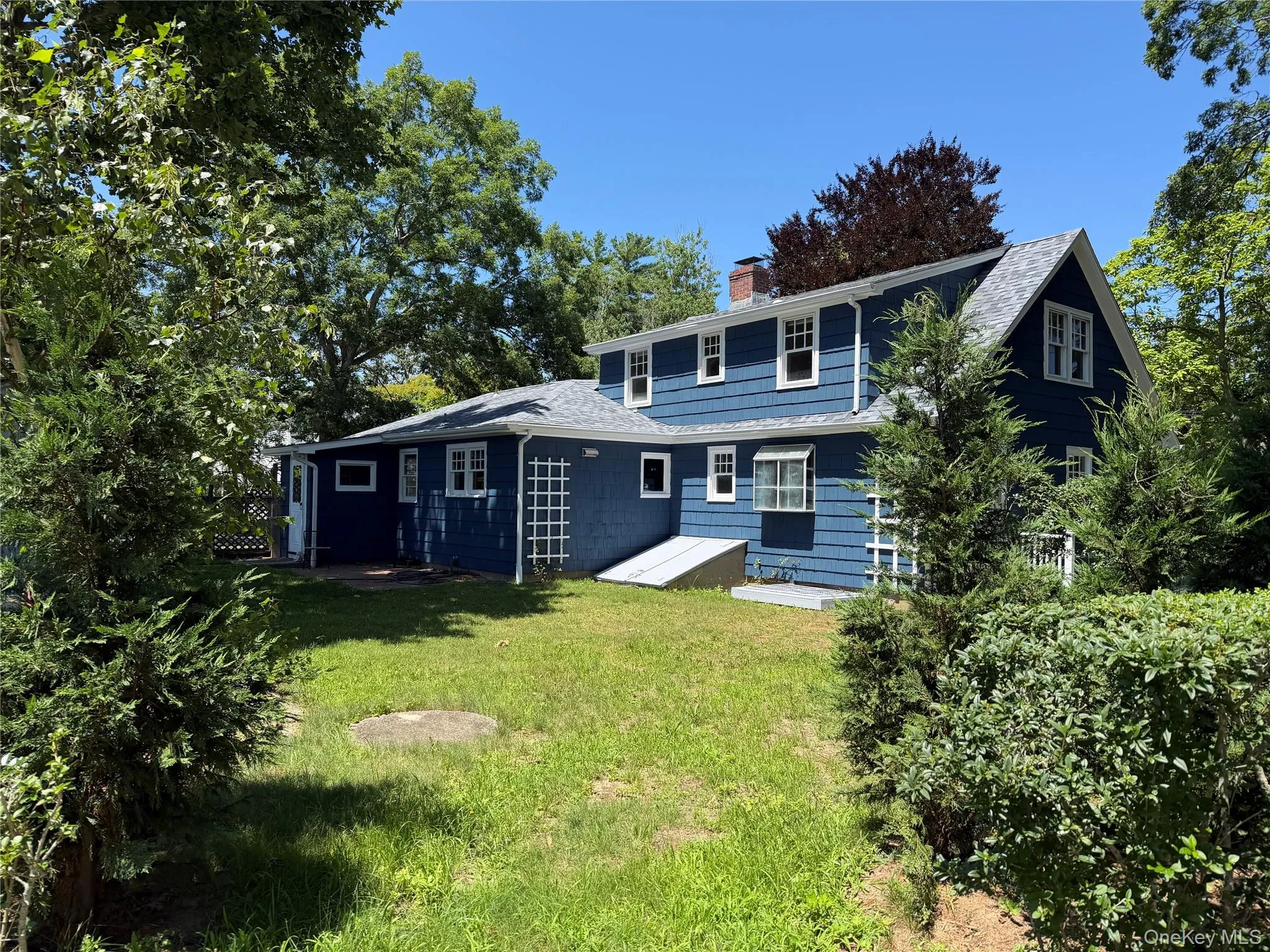 Multi-level residence featuring blue siding, white trim, and a shingled roof Multi-level residence featuring blue siding, white trim, and a shingled roof