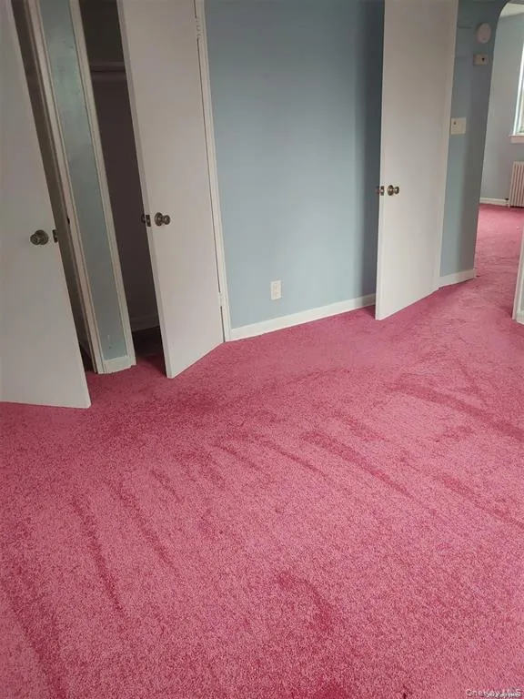 Unfurnished bedroom with carpet flooring, radiator heating unit, and a closet Unfurnished bedroom with carpet flooring, radiator heating unit, and a closet