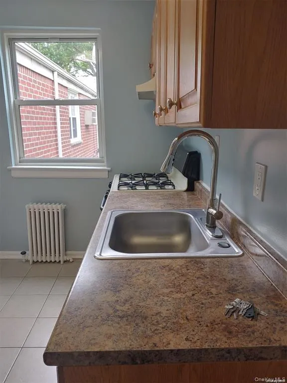 Kitchen with dark countertops, radiator, light tile patterned floors, and gas range gas stove Kitchen with dark countertops, radiator, light tile patterned floors, and gas range gas stove