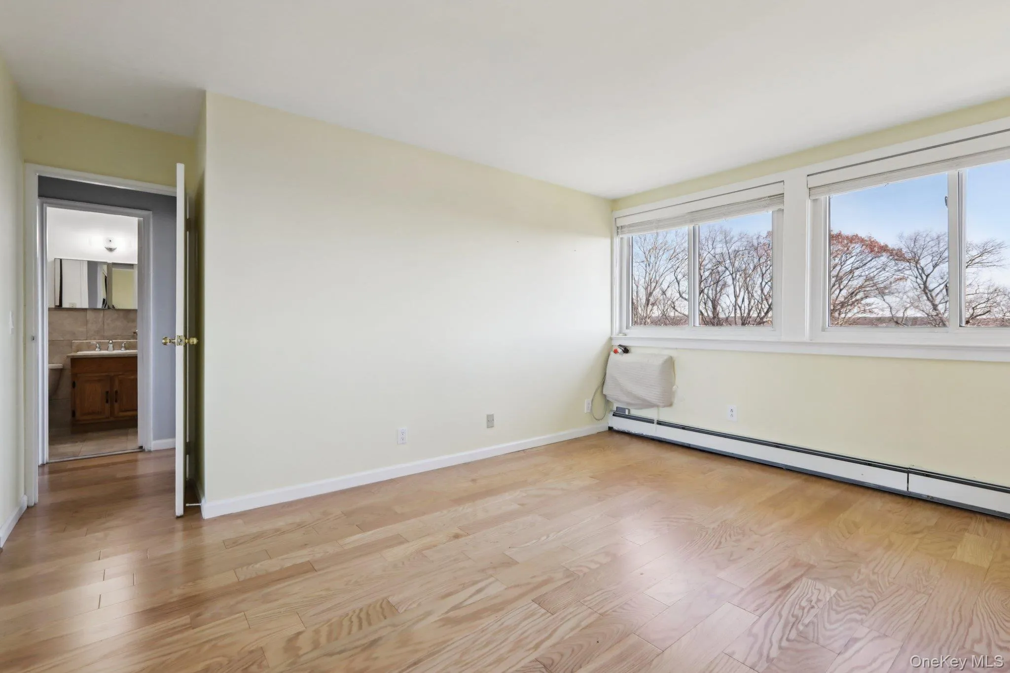 Unfurnished bedroom featuring light wood-style flooring and a baseboard heating unit Unfurnished bedroom featuring light wood-style flooring and a baseboard heating unit