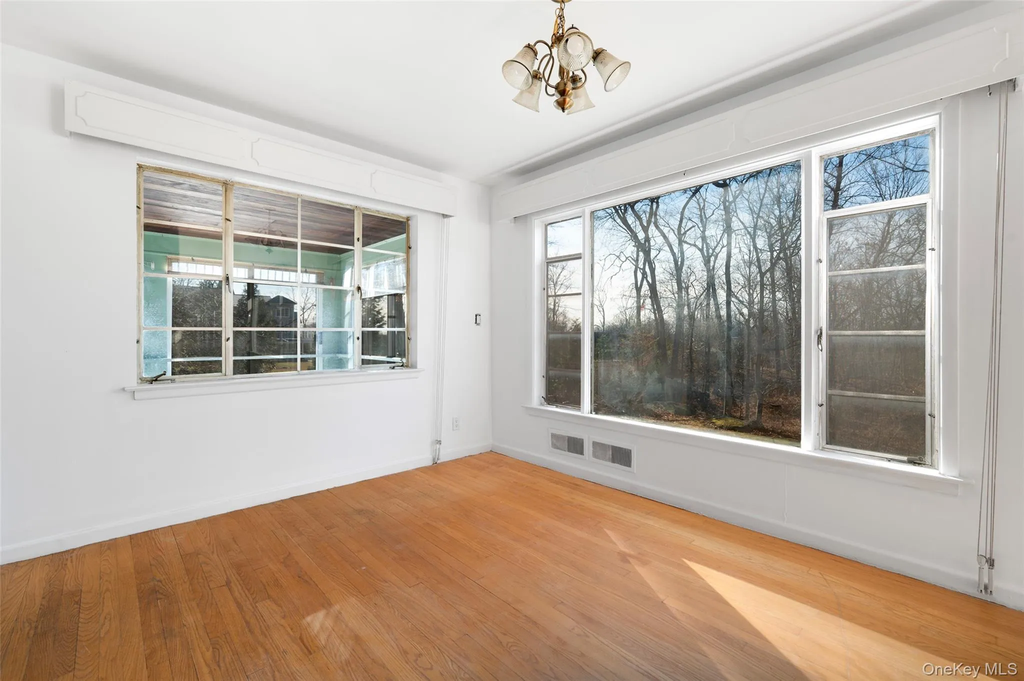 Unfurnished room with wood-type flooring and an inviting chandelier Unfurnished room with wood-type flooring and an inviting chandelier