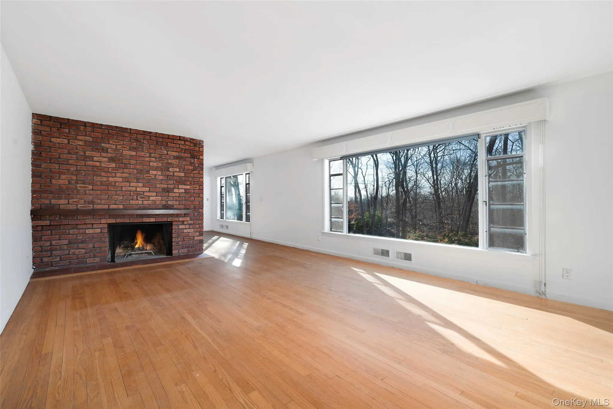 Unfurnished living room with a fireplace and light hardwood / wood-style flooring Unfurnished living room with a fireplace and light hardwood / wood-style flooring