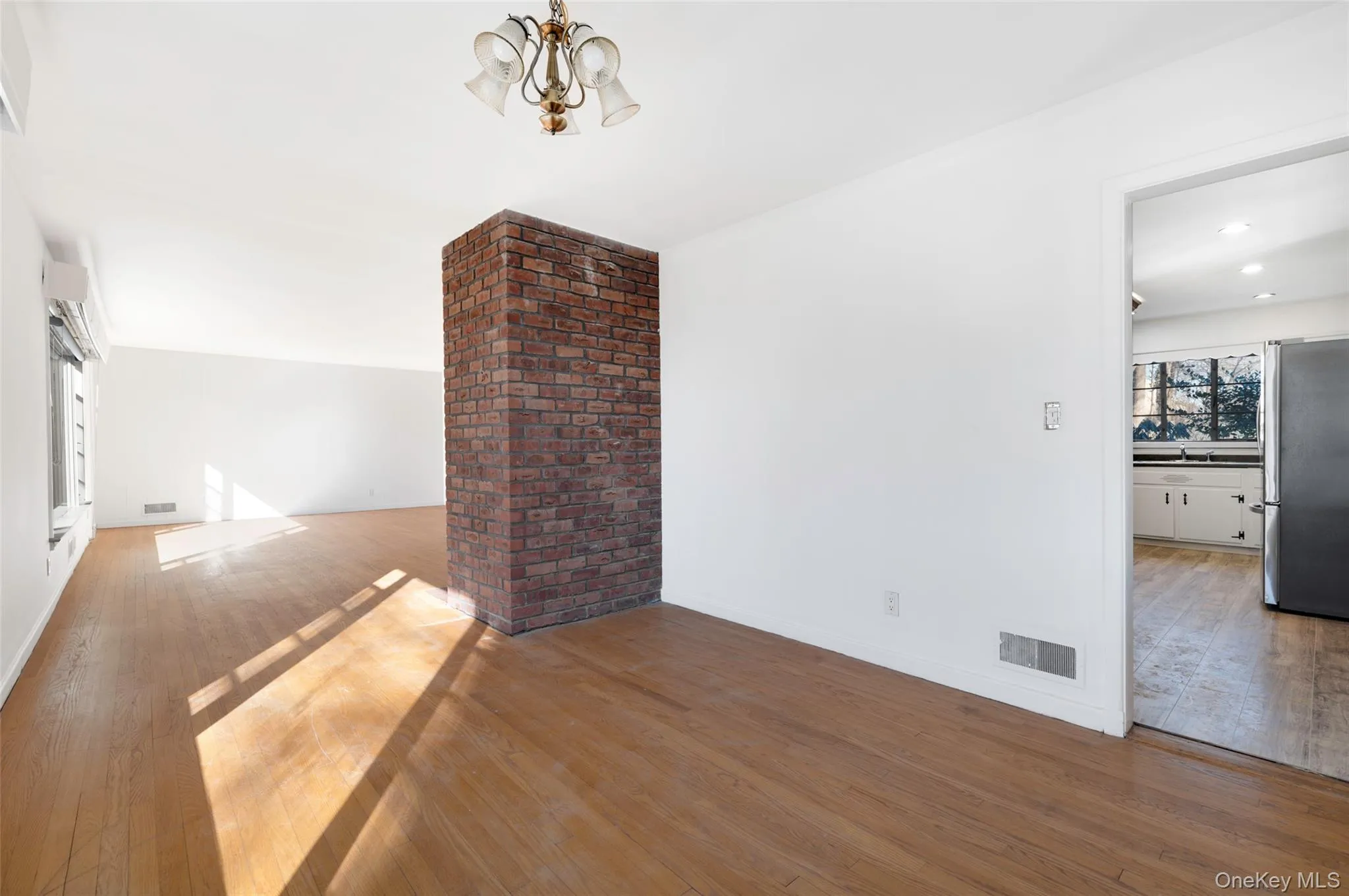 Unfurnished living room with wood-type flooring and a notable chandelier Unfurnished living room with wood-type flooring and a notable chandelier