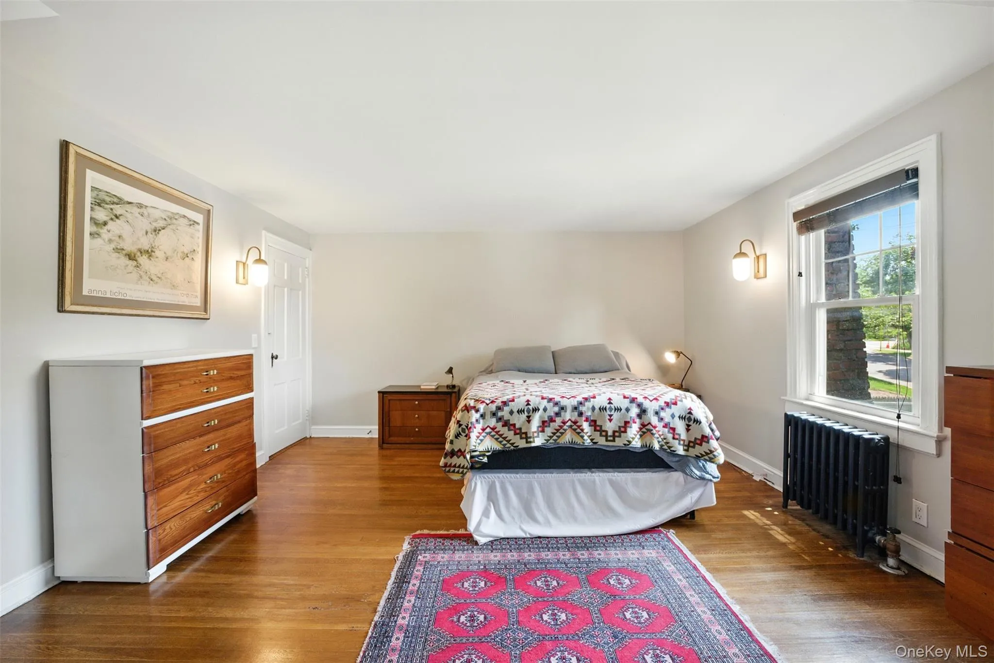 Alternate view of the Primary Bedroom with radiator and wood finished floors Alternate view of the Primary Bedroom with radiator and wood finished floors