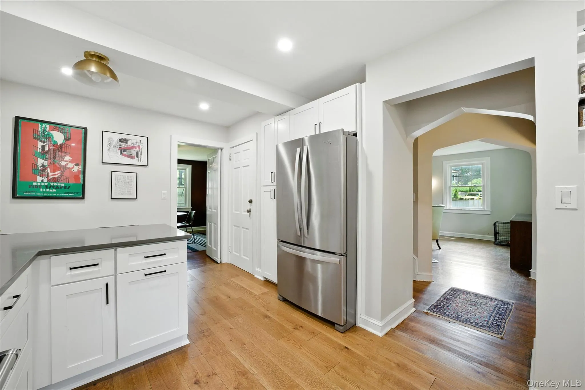 Kitchen featuring freestanding refrigerator, white cabinetry, dark countertops, recessed lighting, and light wood finished floors Kitchen featuring freestanding refrigerator, white cabinetry, dark countertops, recessed lighting, and light wood finished floors