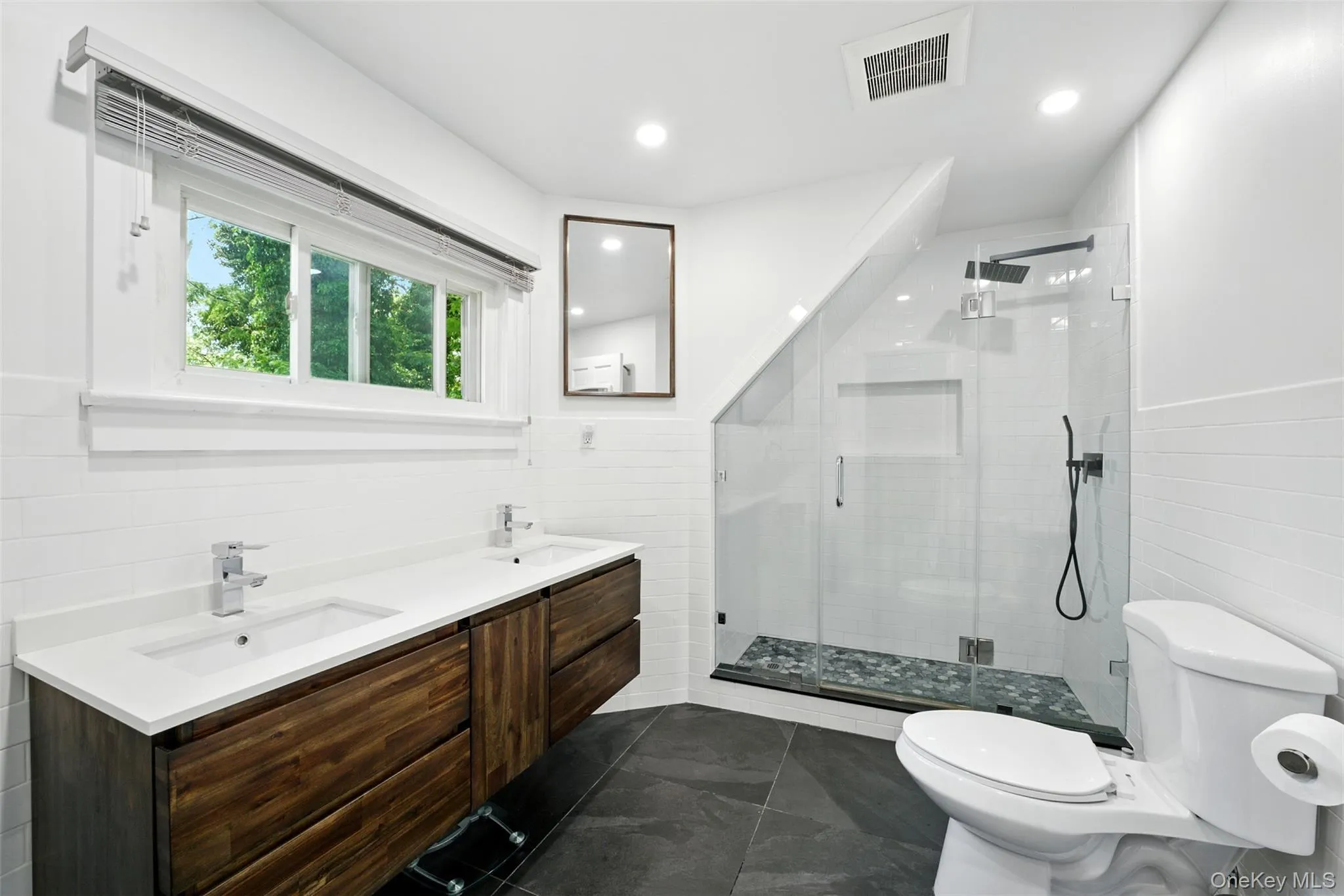 Primary En-Suite Bathroom with tile walls, a stall shower, double vanity, recessed lighting, and a wainscoted wall Primary En-Suite Bathroom with tile walls, a stall shower, double vanity, recessed lighting, and a wainscoted wall